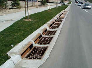 Roadside utility trench with installed drainage grates for water management.