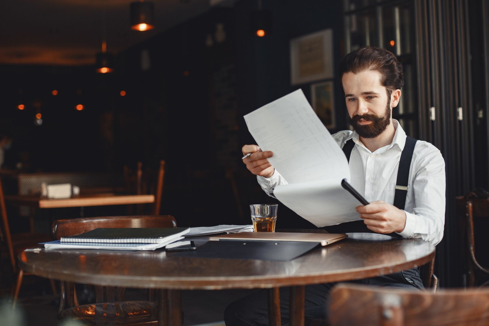 A man is sitting at a table looking at a piece of paper.