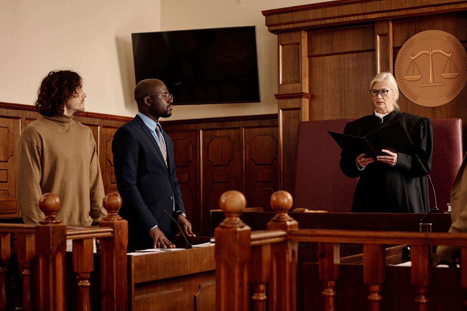 A man in a suit and tie is standing in front of a judge in a courtroom.
