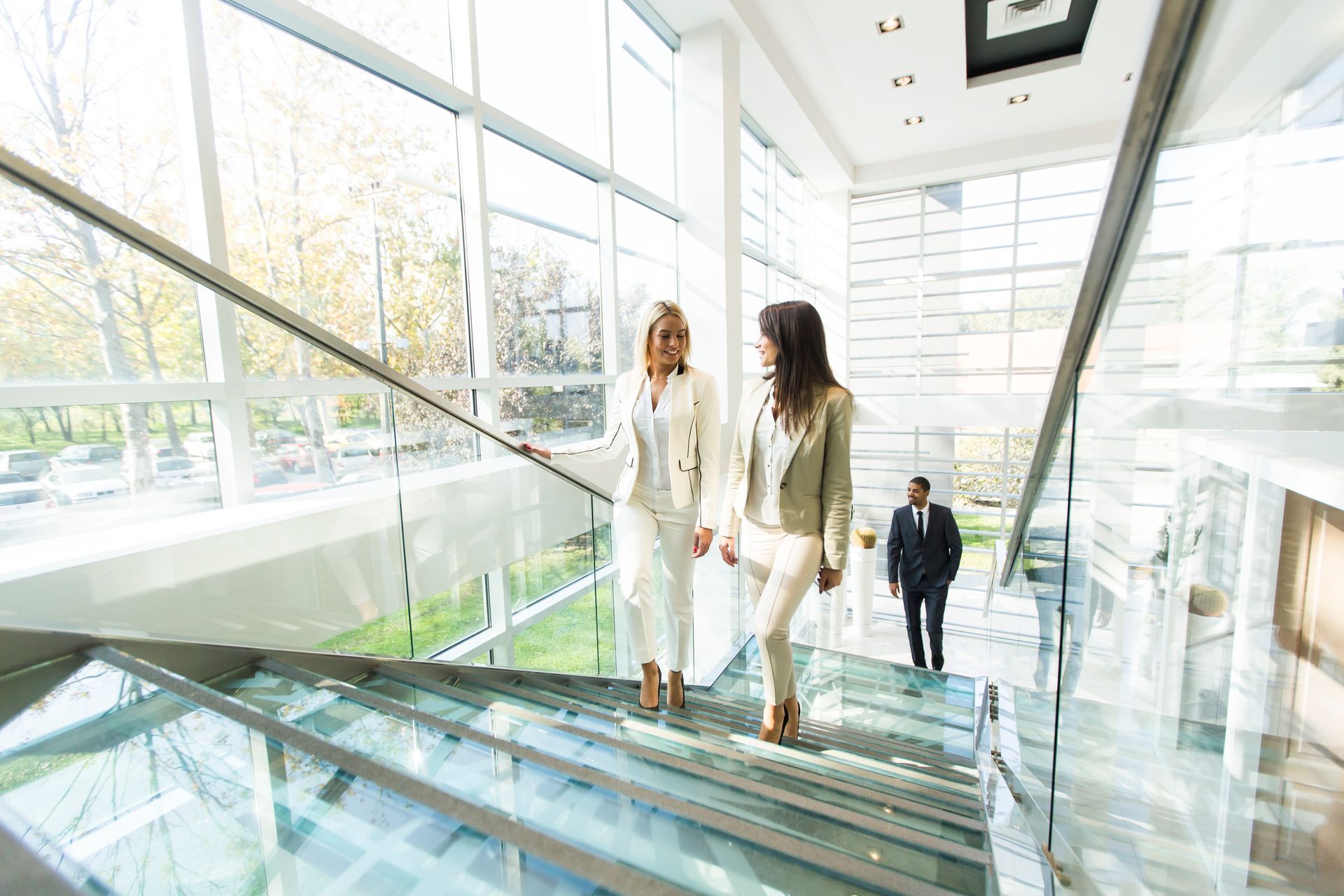 Two women are walking down a set of stairs in an office building.