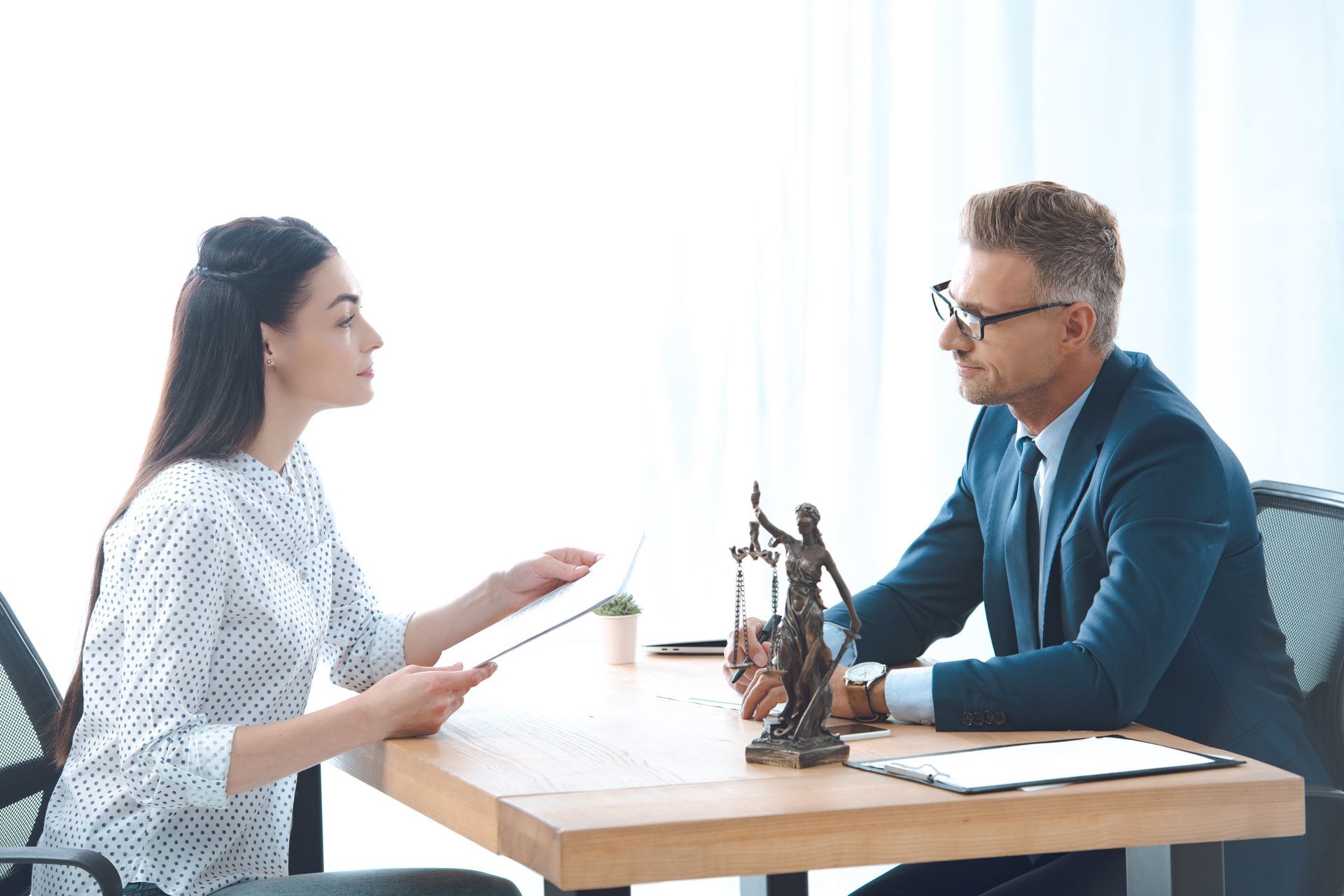 A man and a woman are sitting at a table talking to each other.