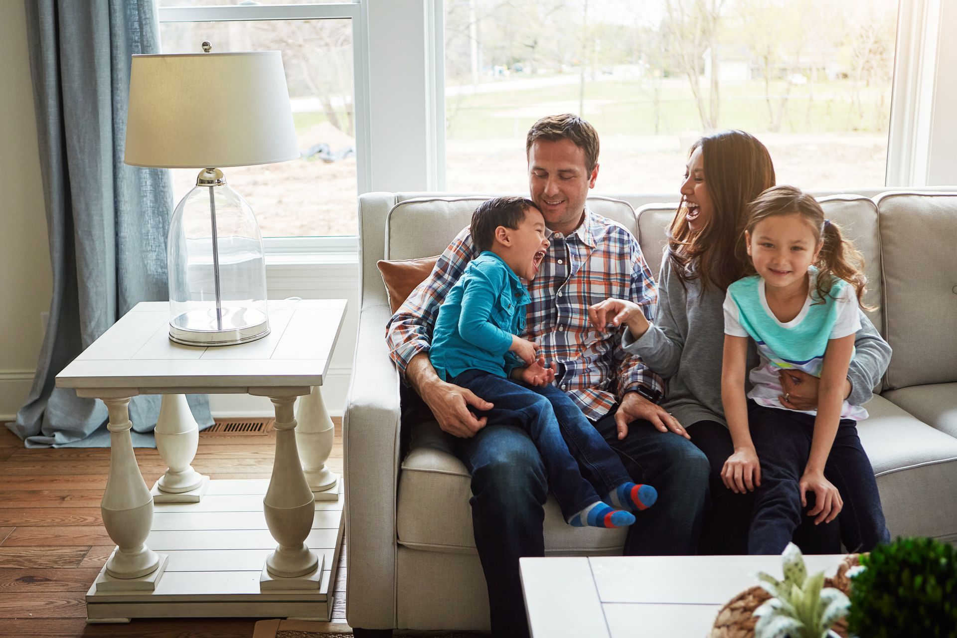 A family is sitting on a couch in a living room.
