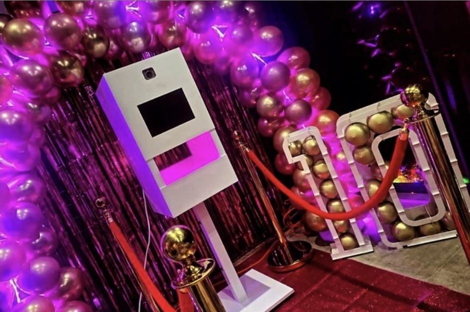 Een fotohokje is omringd door ballonnen en een rode loper.