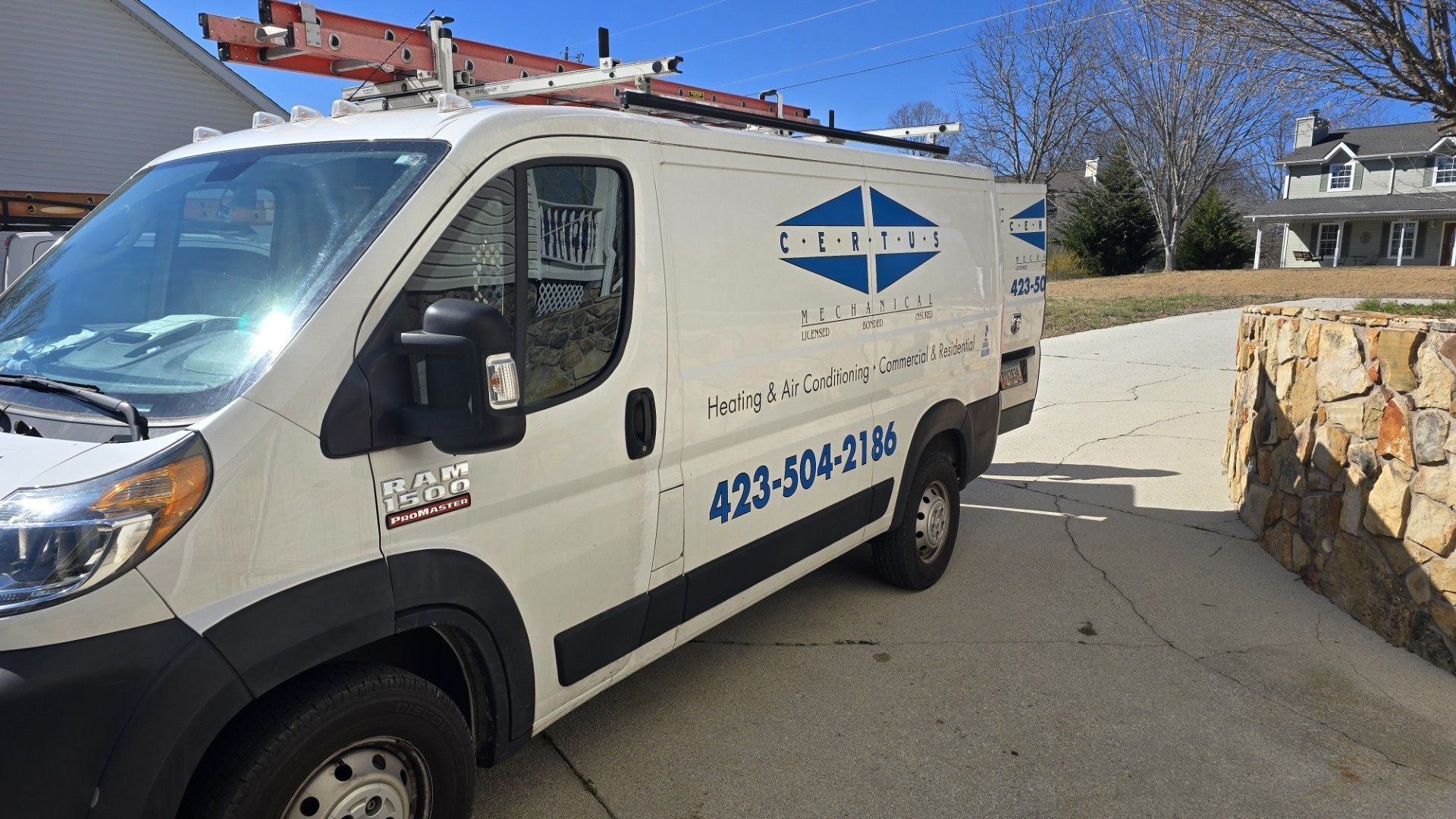 White work van with ladder on top, parked in a driveway. Phone number 423-584-3165.