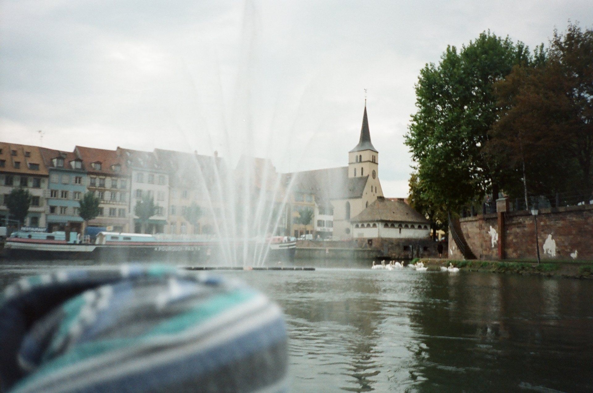 A fountain in the middle of a lake with a church in the background
