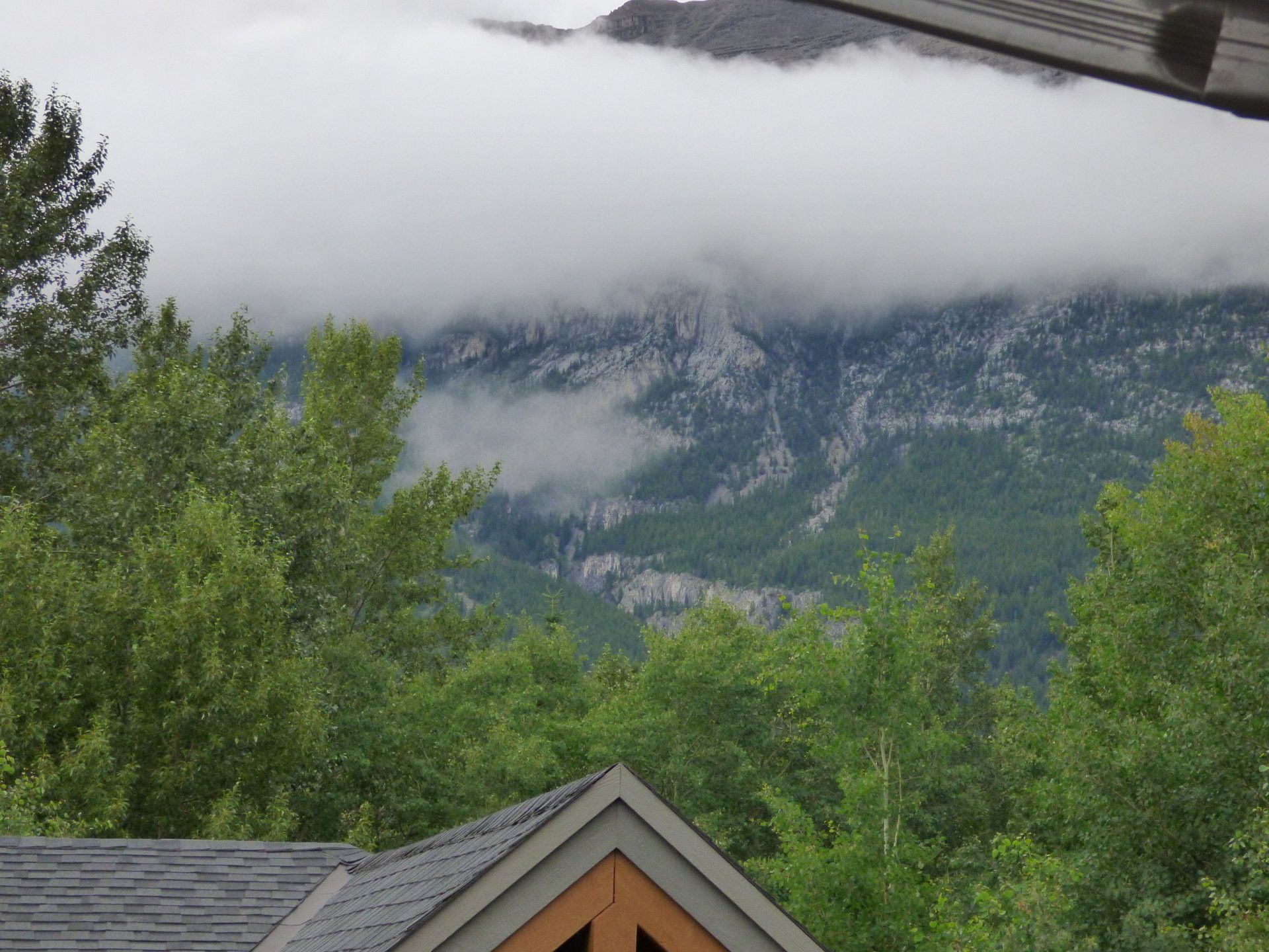 A house with a mountain in the background and trees in the foreground
