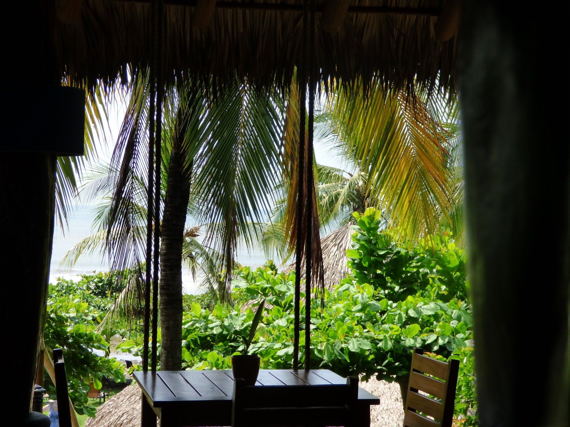 A view of a table and chairs from a thatched roof