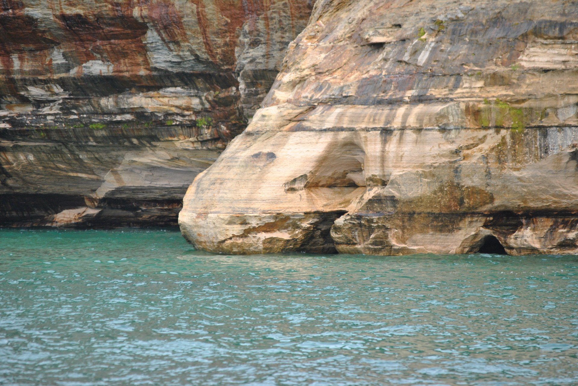 A large rock in the middle of a body of water.