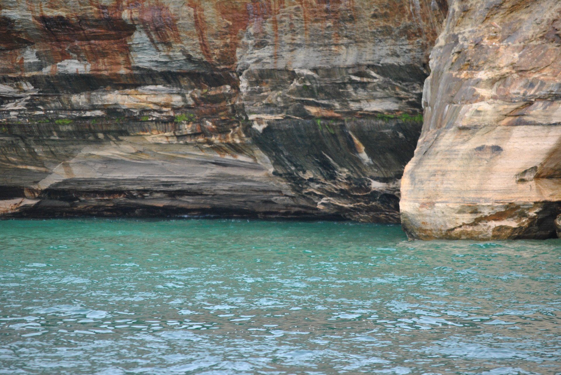 There is a large rock in the middle of the water.