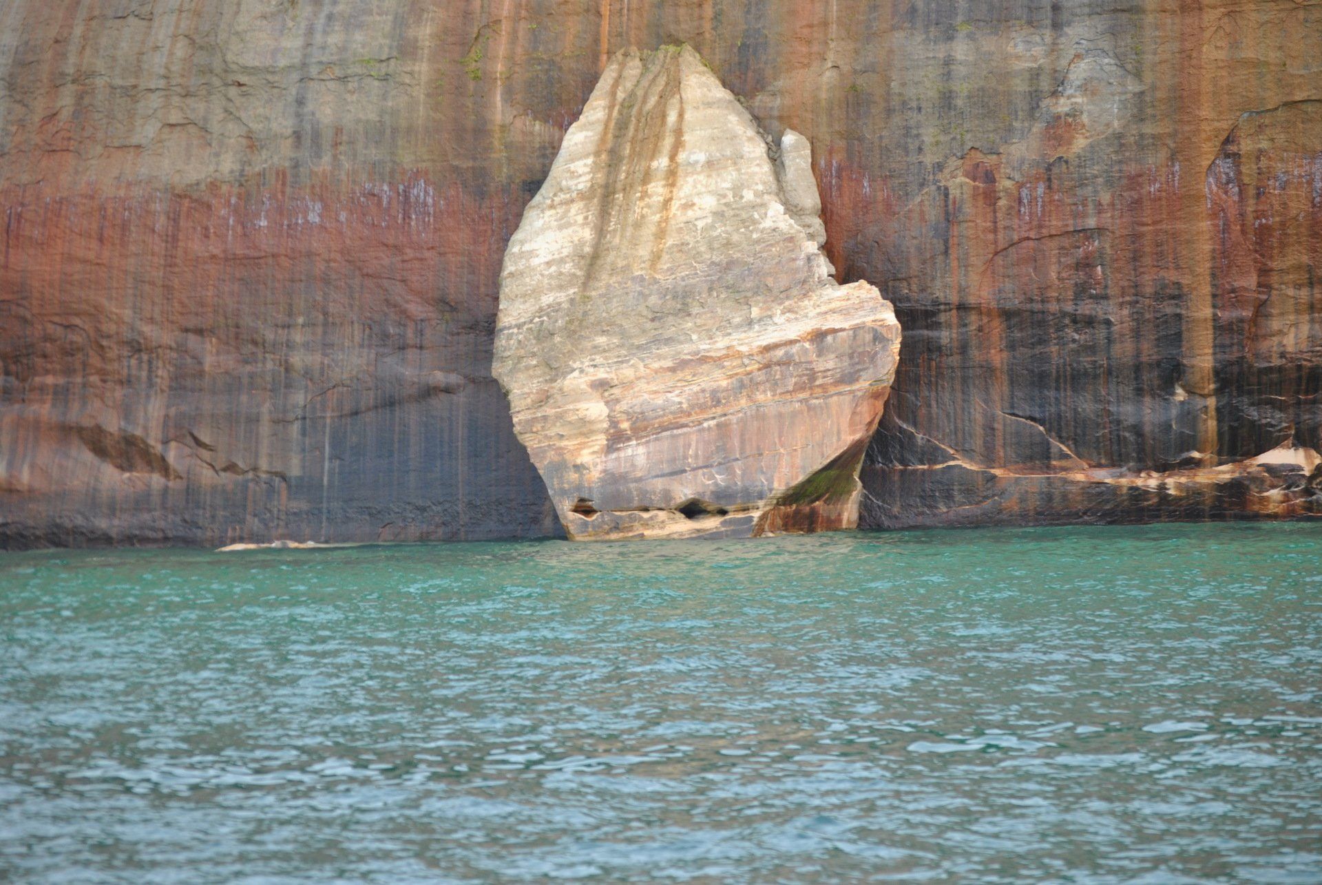 There is a large rock in the middle of the water.
