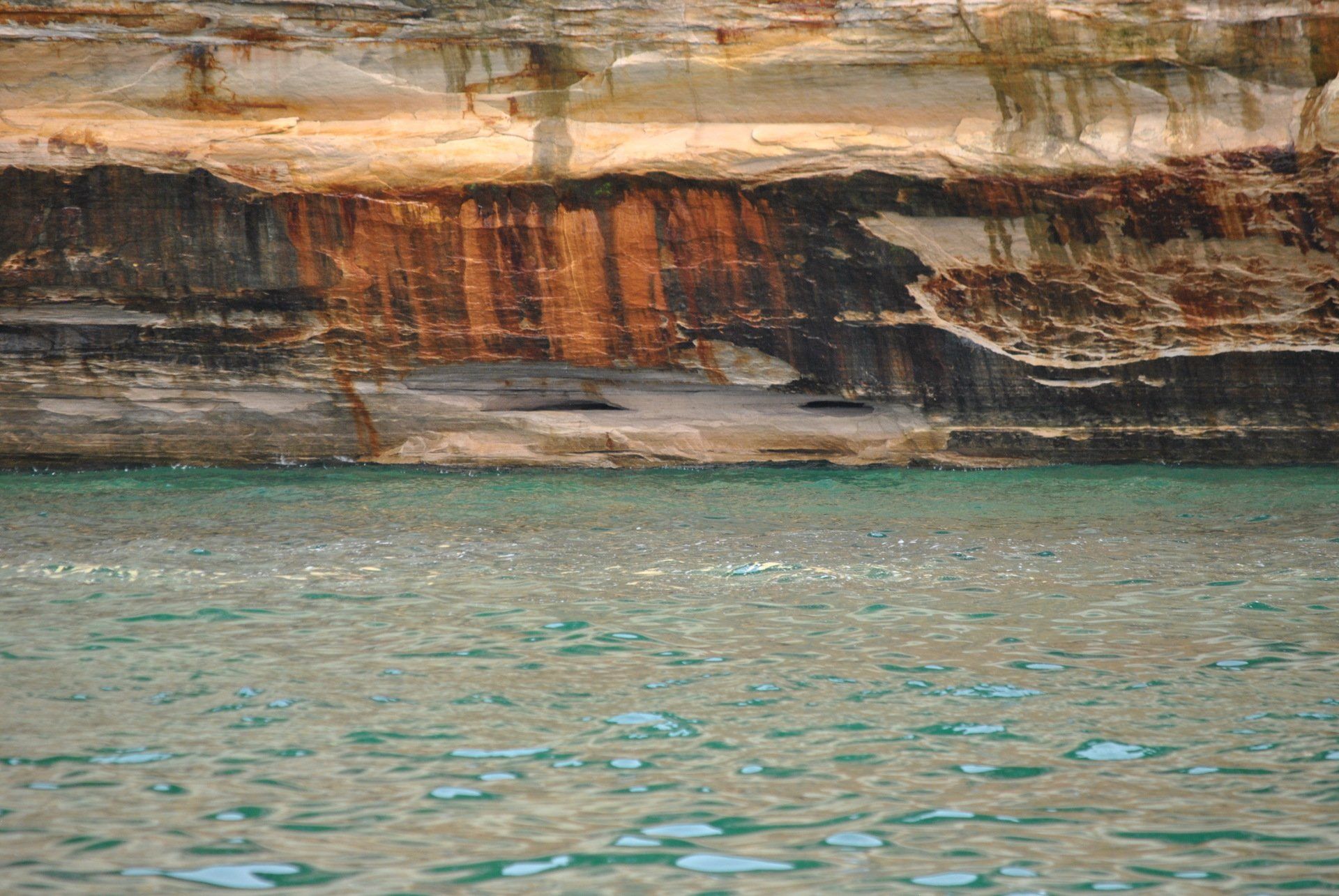 A large body of water with a rocky cliff in the background.