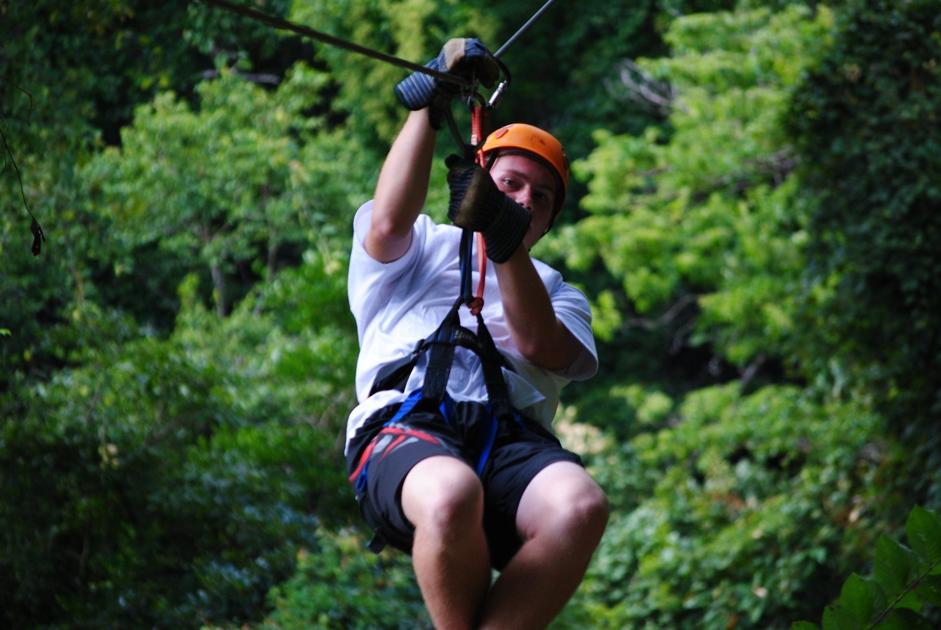 A man is flying through the air on a zip line.