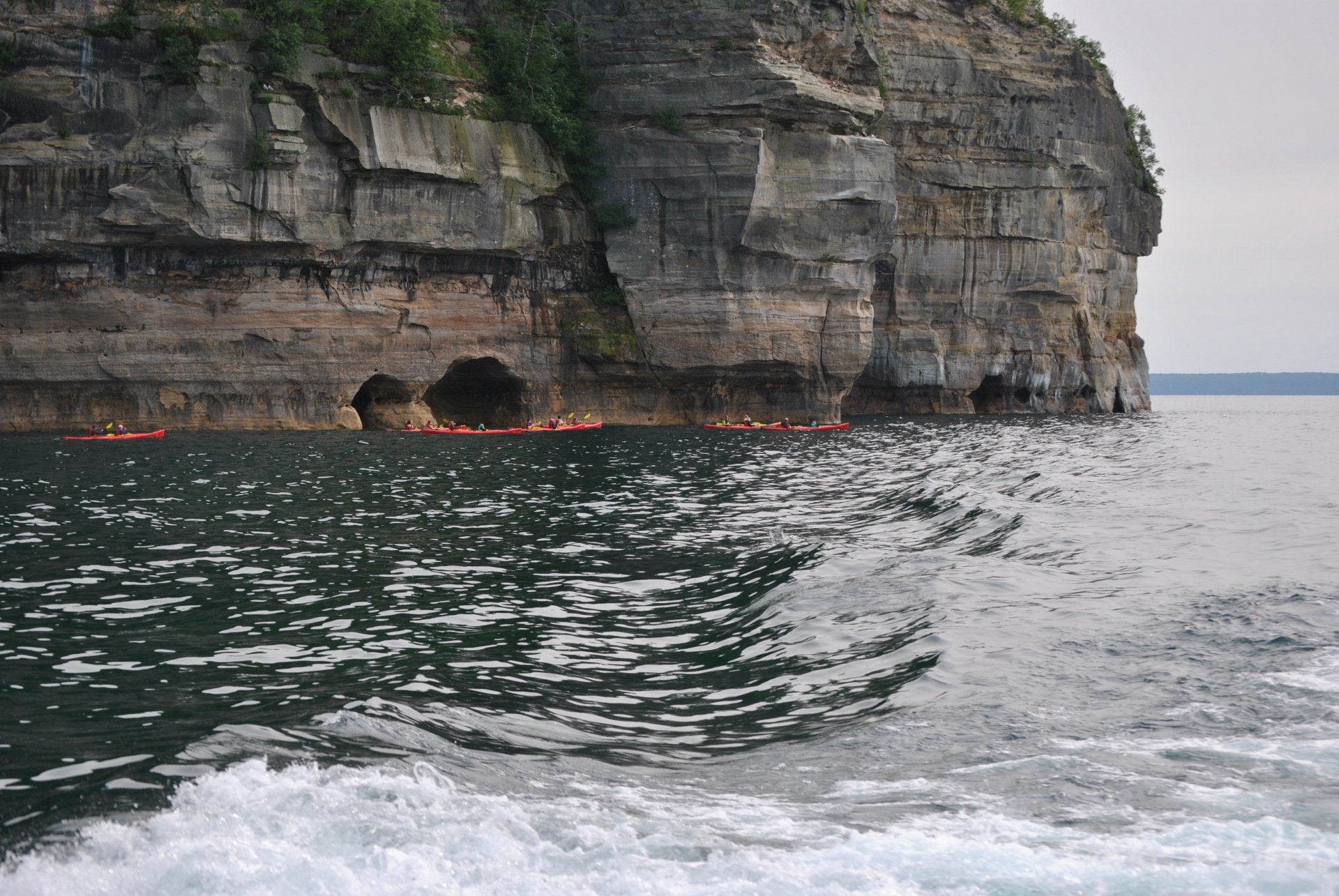 A couple of kayaks are in the water near a cliff