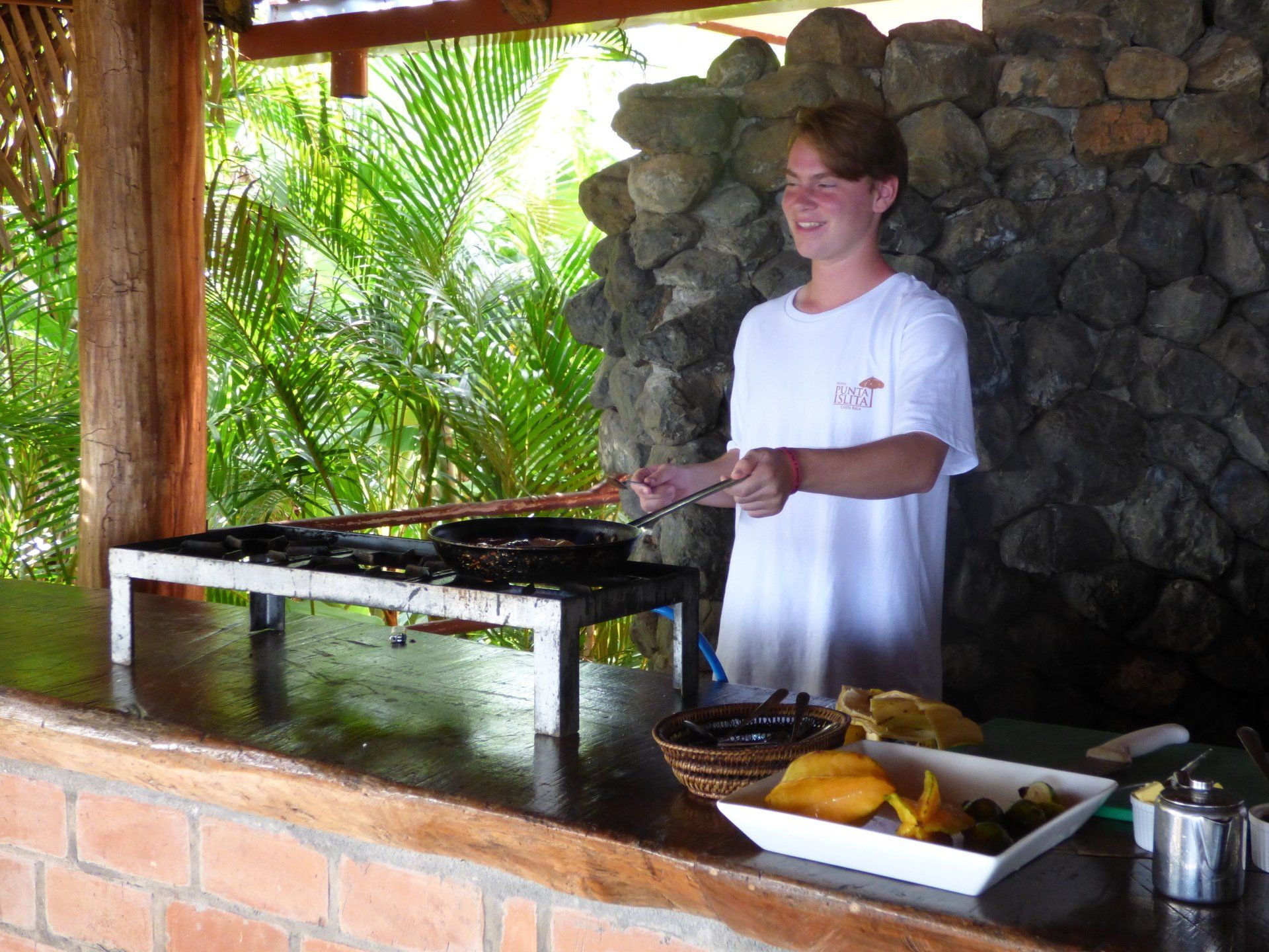 A man in a white shirt is cooking on a stove outside