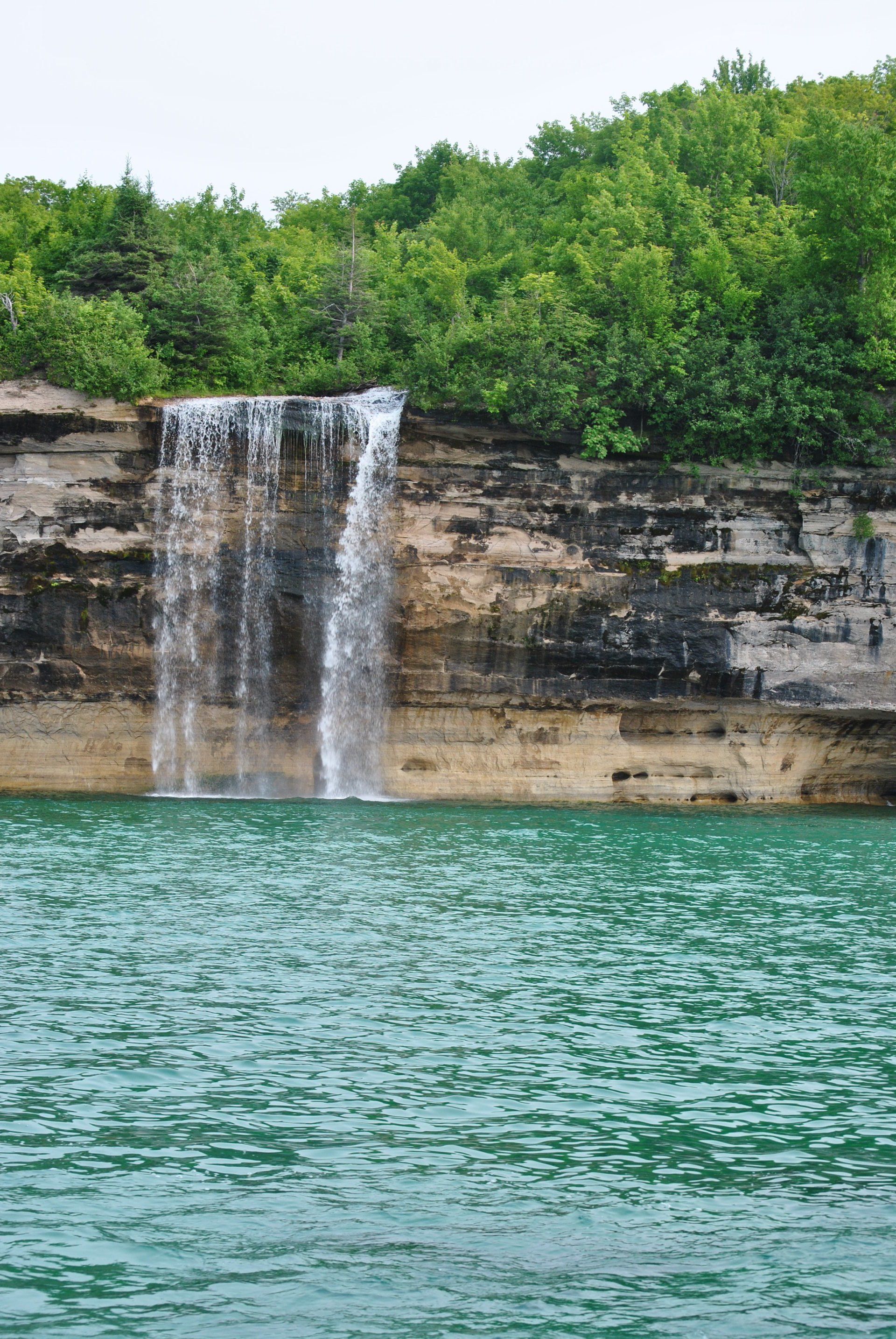 A waterfall in the middle of a lake with trees in the background