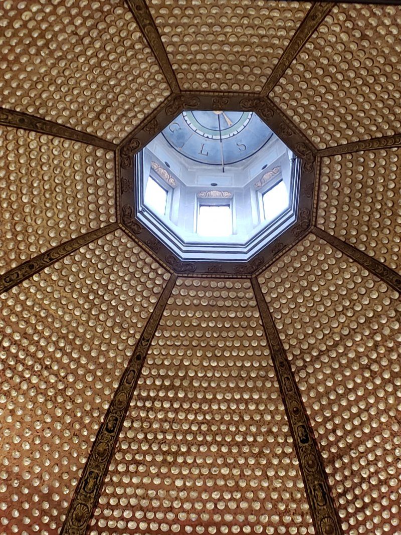 Looking up at the ceiling of a building with a window in the middle.