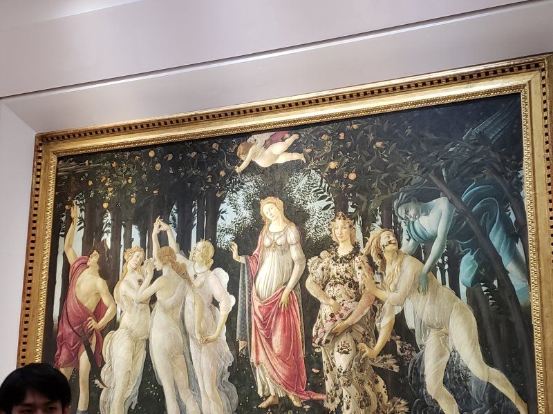 A man is standing in front of a large painting