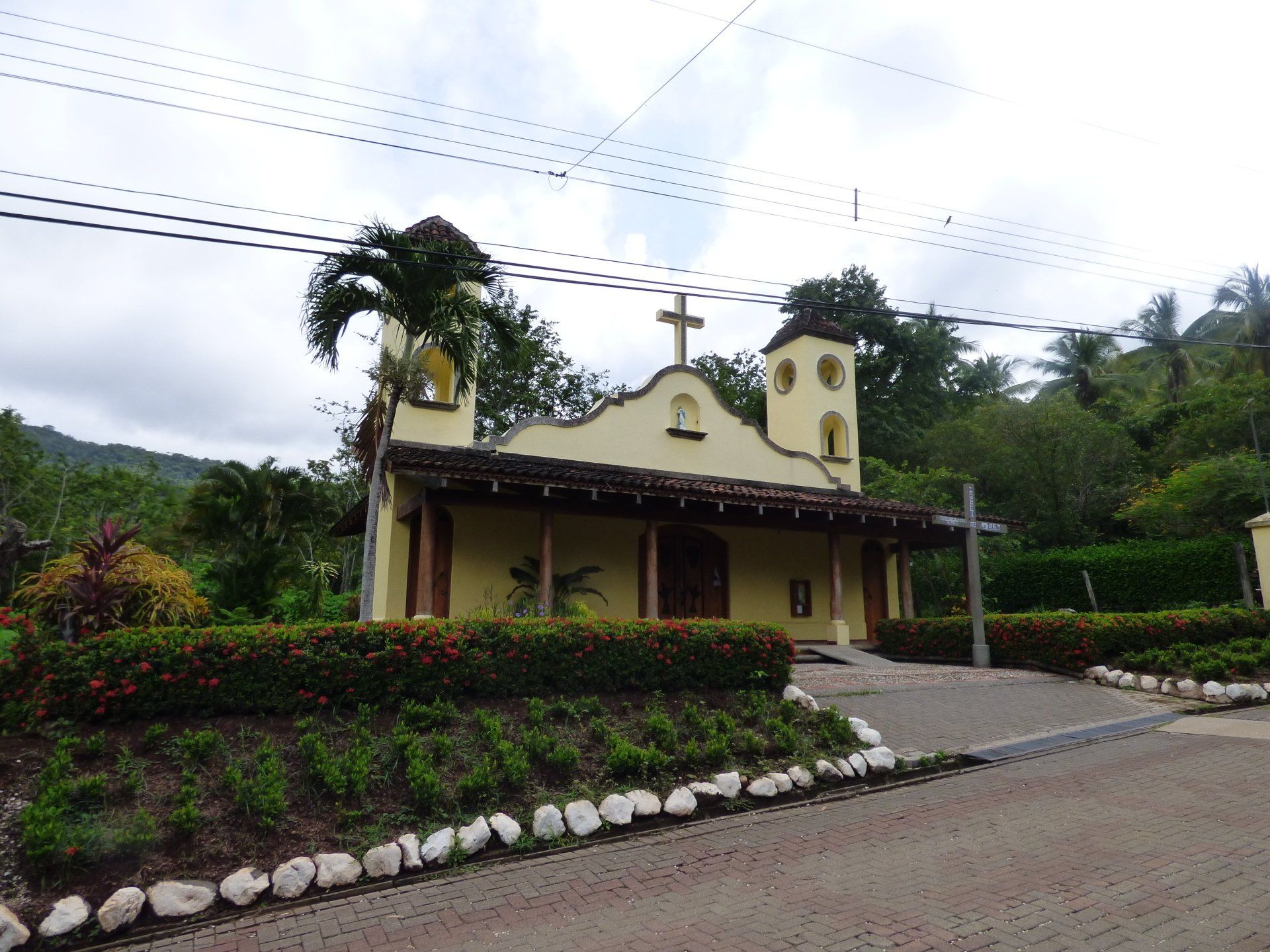 A small yellow church with a cross on top of it