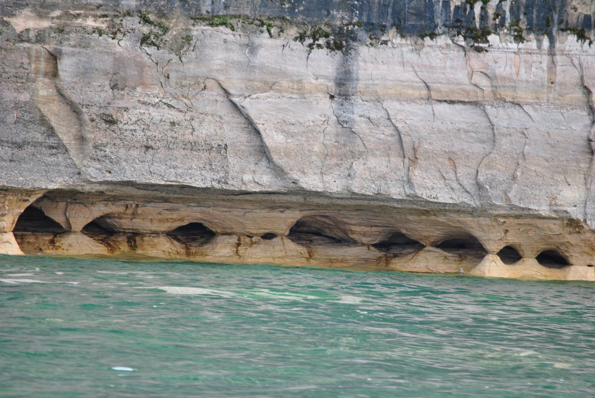 A cliff overlooking a body of water with holes in it