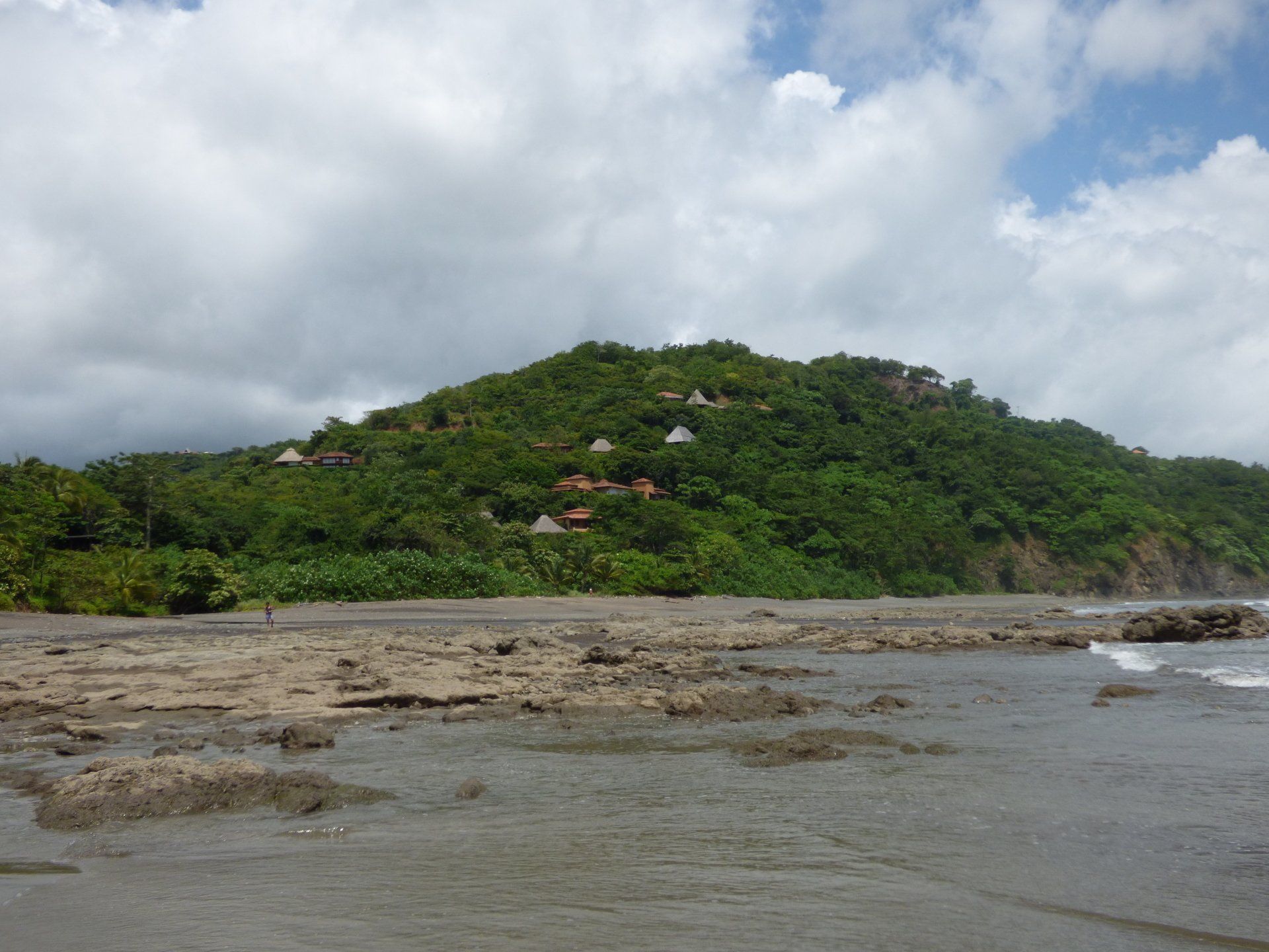 A beach with a hill in the background and houses on it