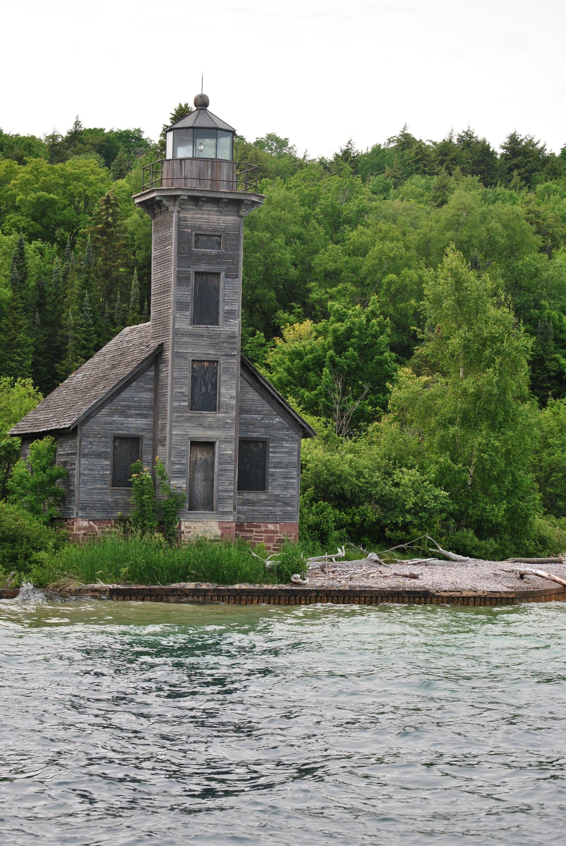 A lighthouse sits on a small island in the middle of a body of water