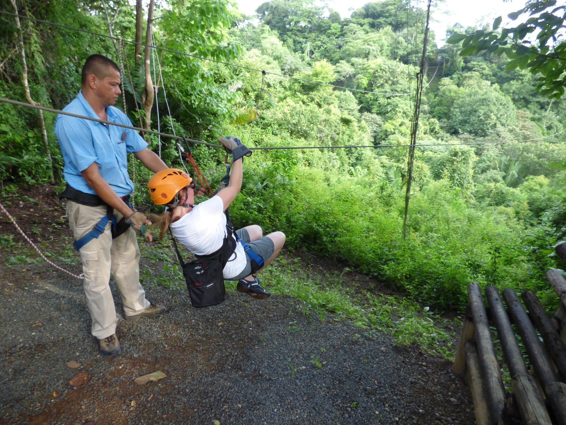 A man is standing next to a person on a zip line