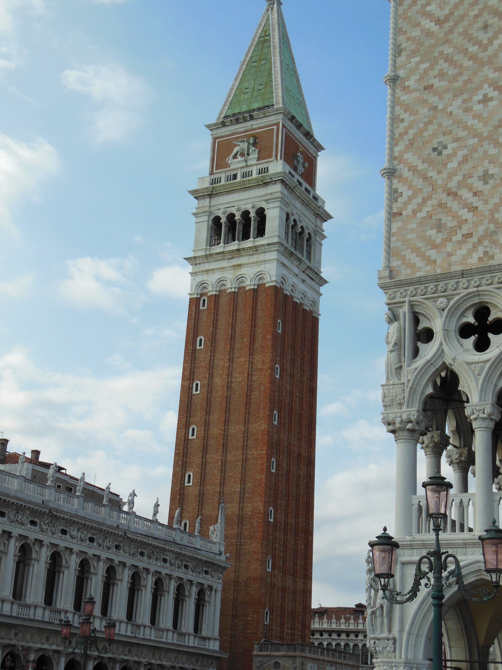 A very tall brick tower with a green roof