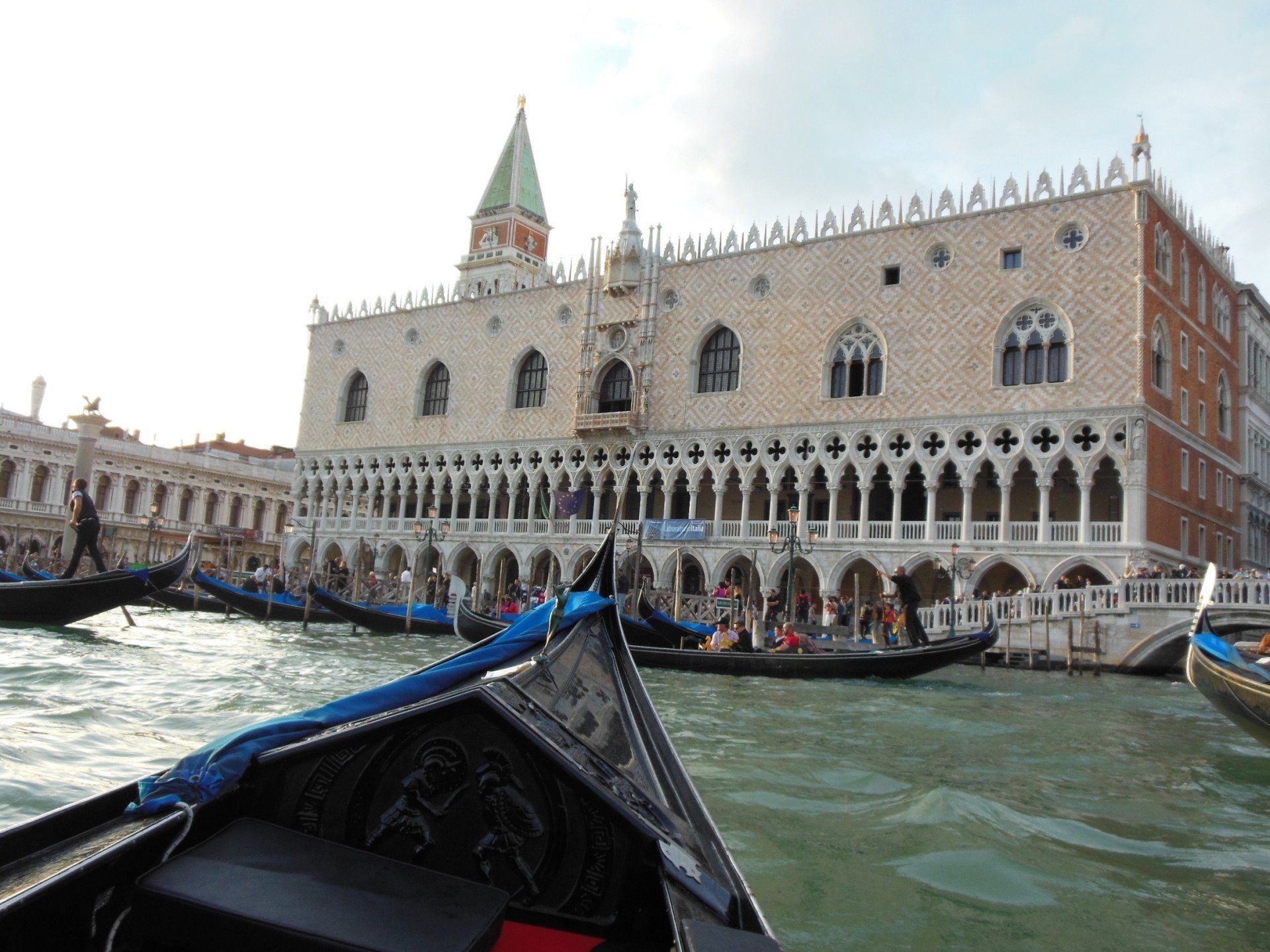 A group of gondolas are floating in front of a large building.