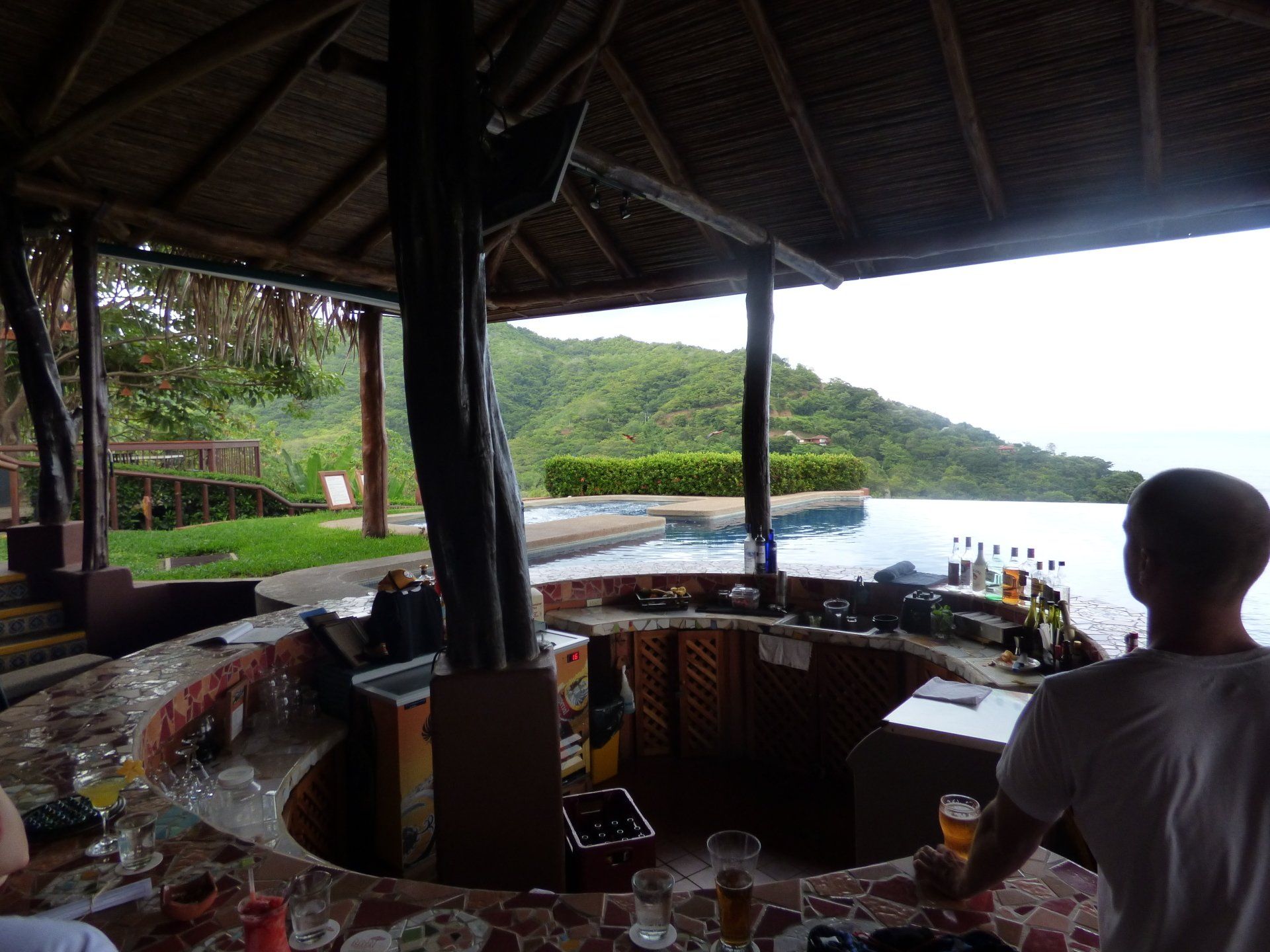 A man sitting at a bar with a view of a swimming pool