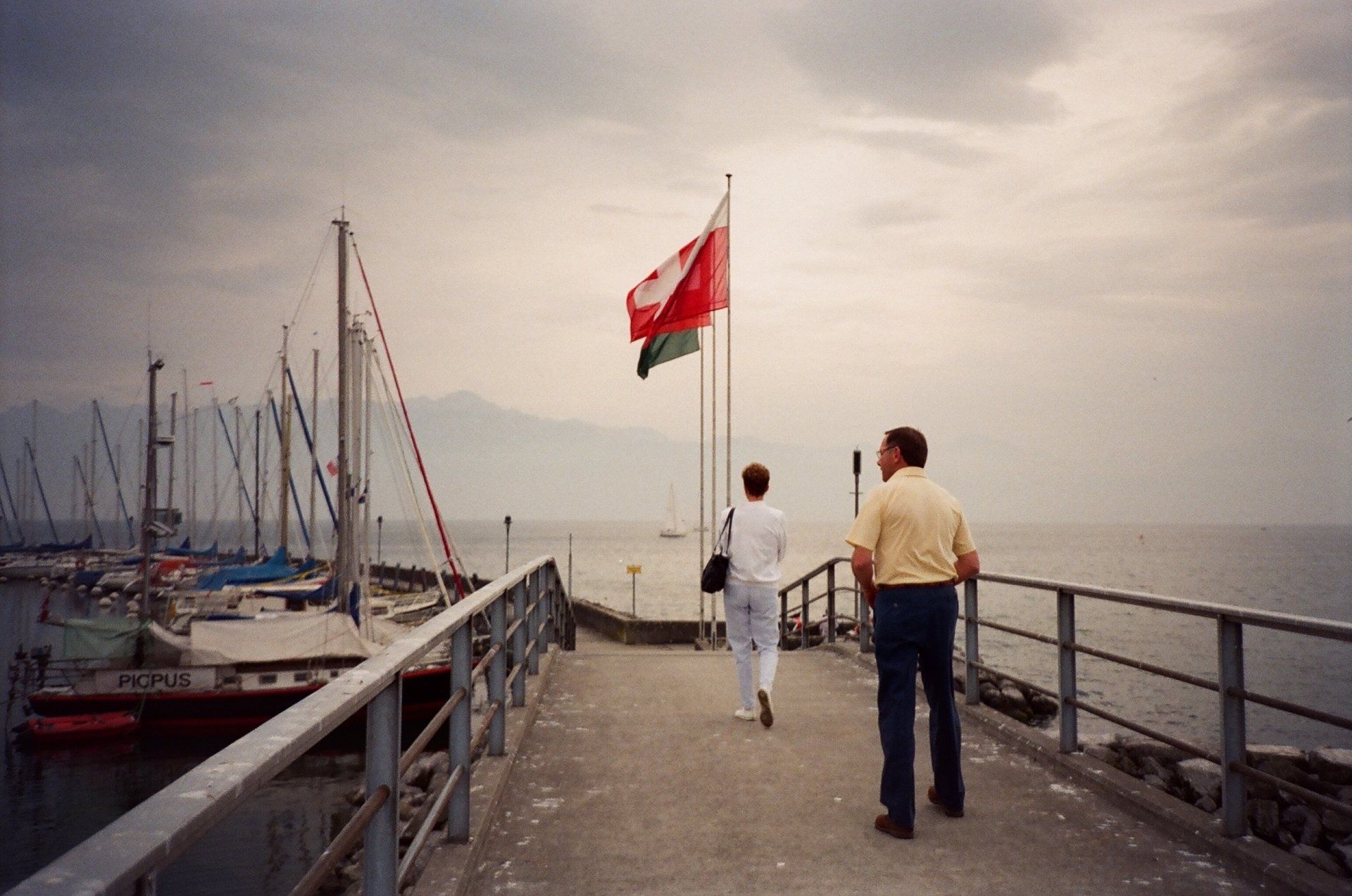 A couple walking on a pier with a canadian flag in the background