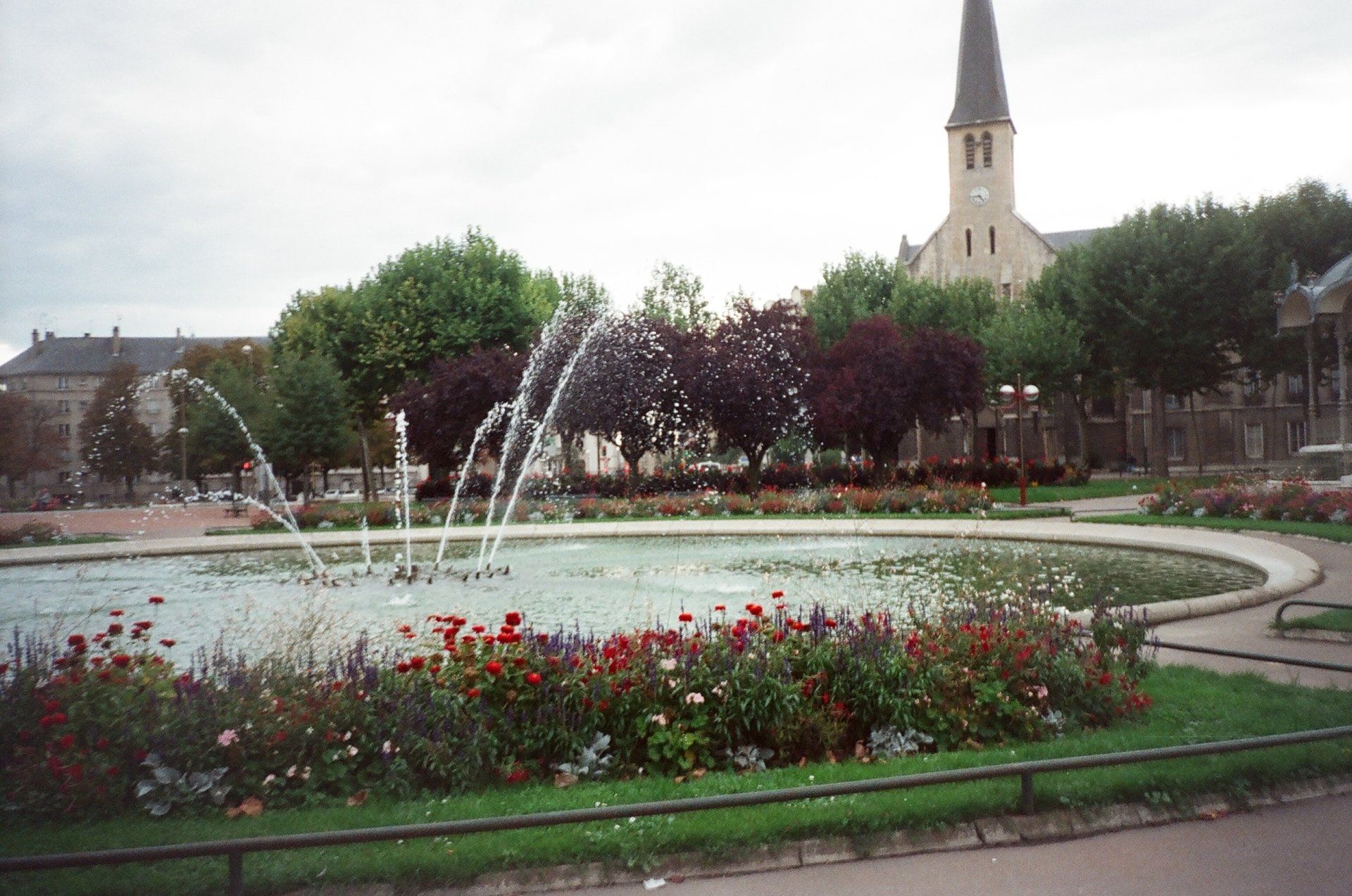 A fountain in a park with a church in the background