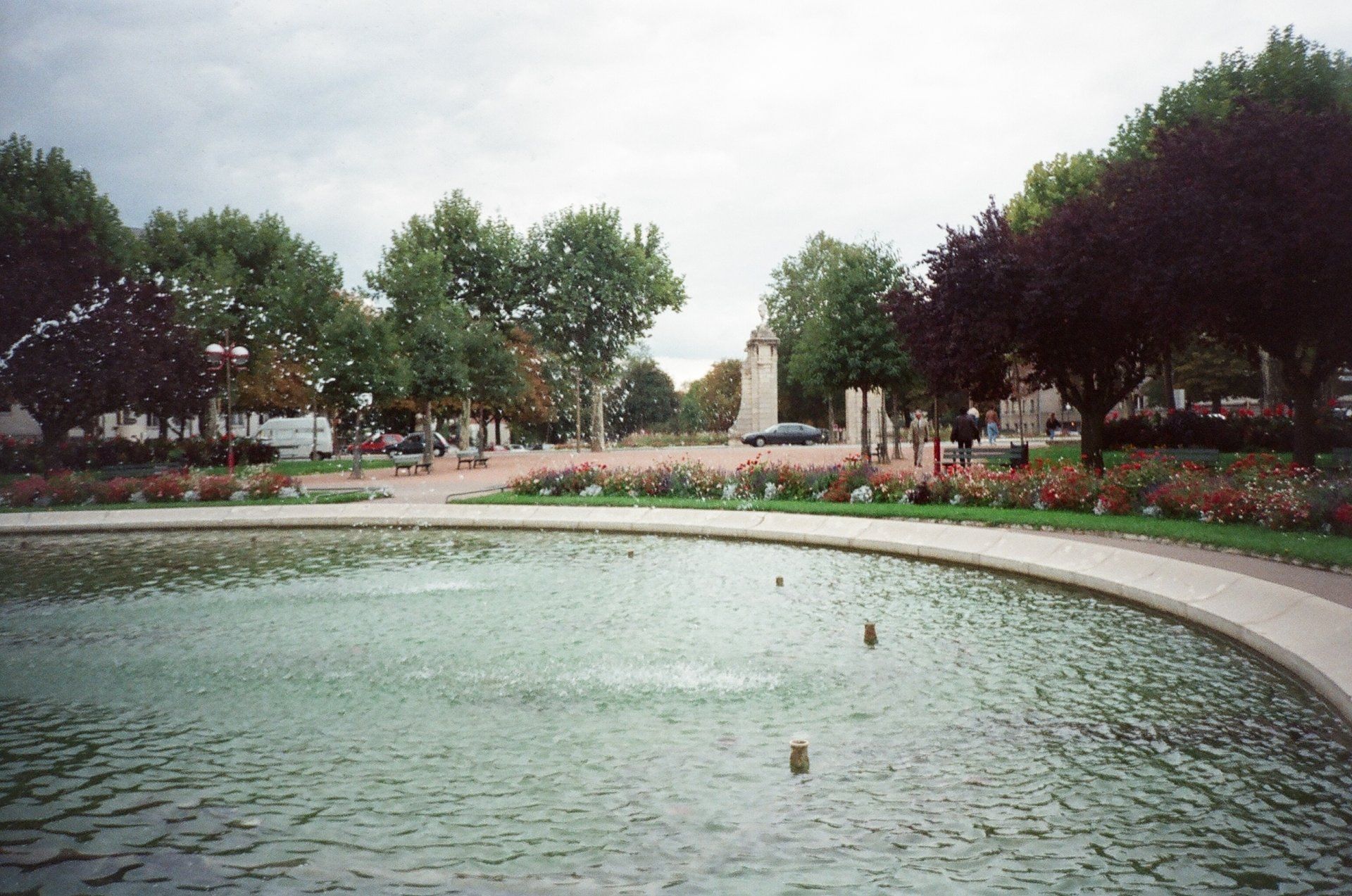 A fountain in a park with trees in the background