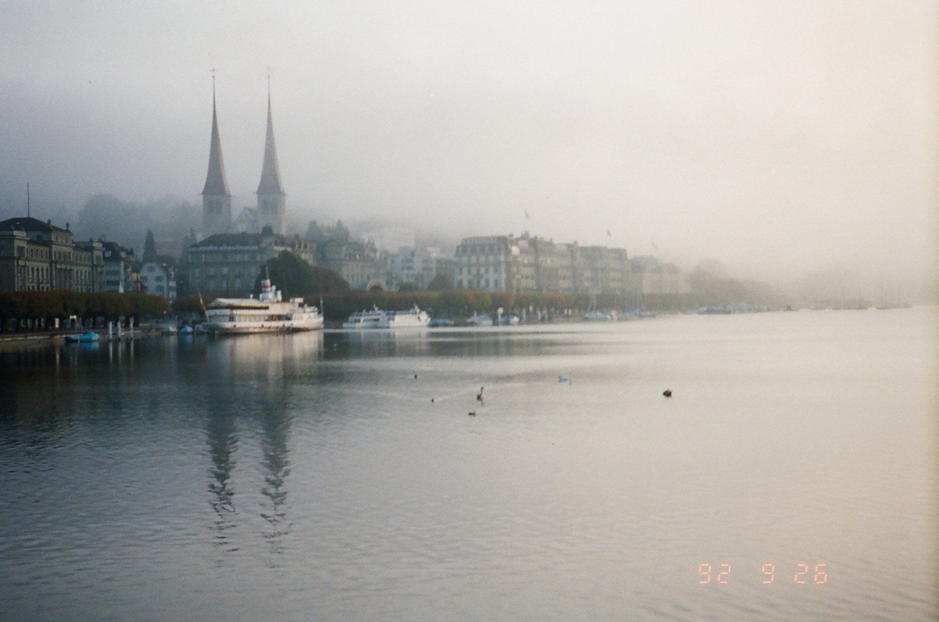 A boat is floating on a lake with a city in the background.