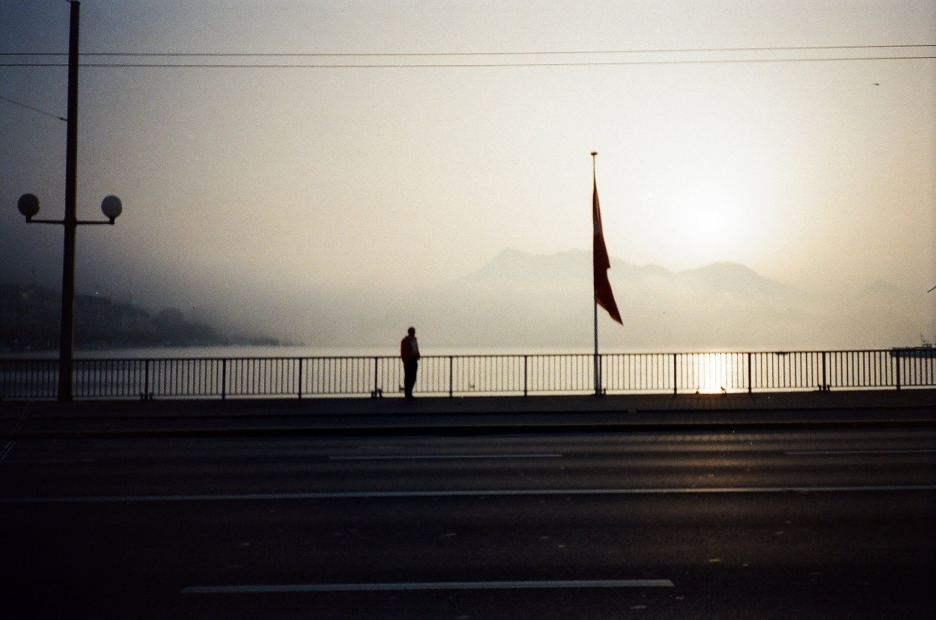 A person standing on a bridge overlooking a body of water