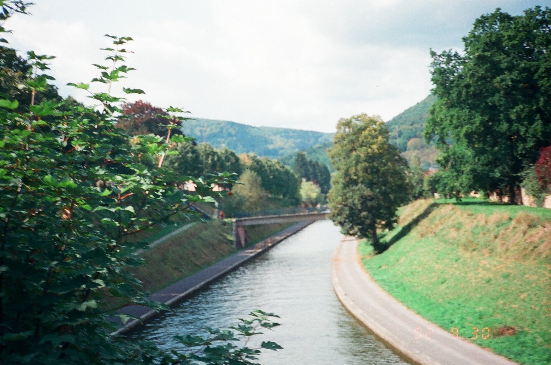 A river runs through a lush green valley surrounded by trees and grass.