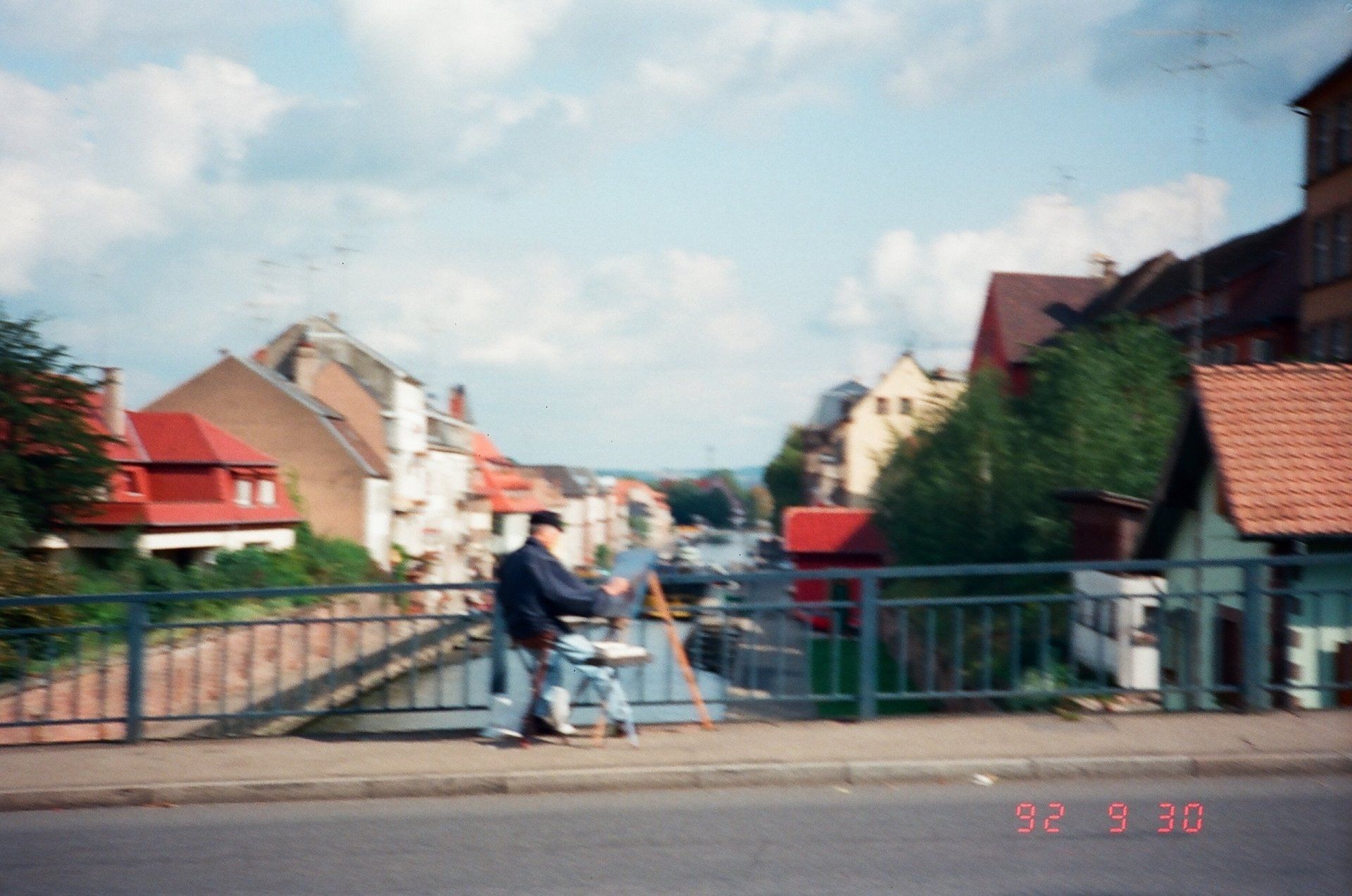 A man is standing on a bridge with a painting easel in front of him