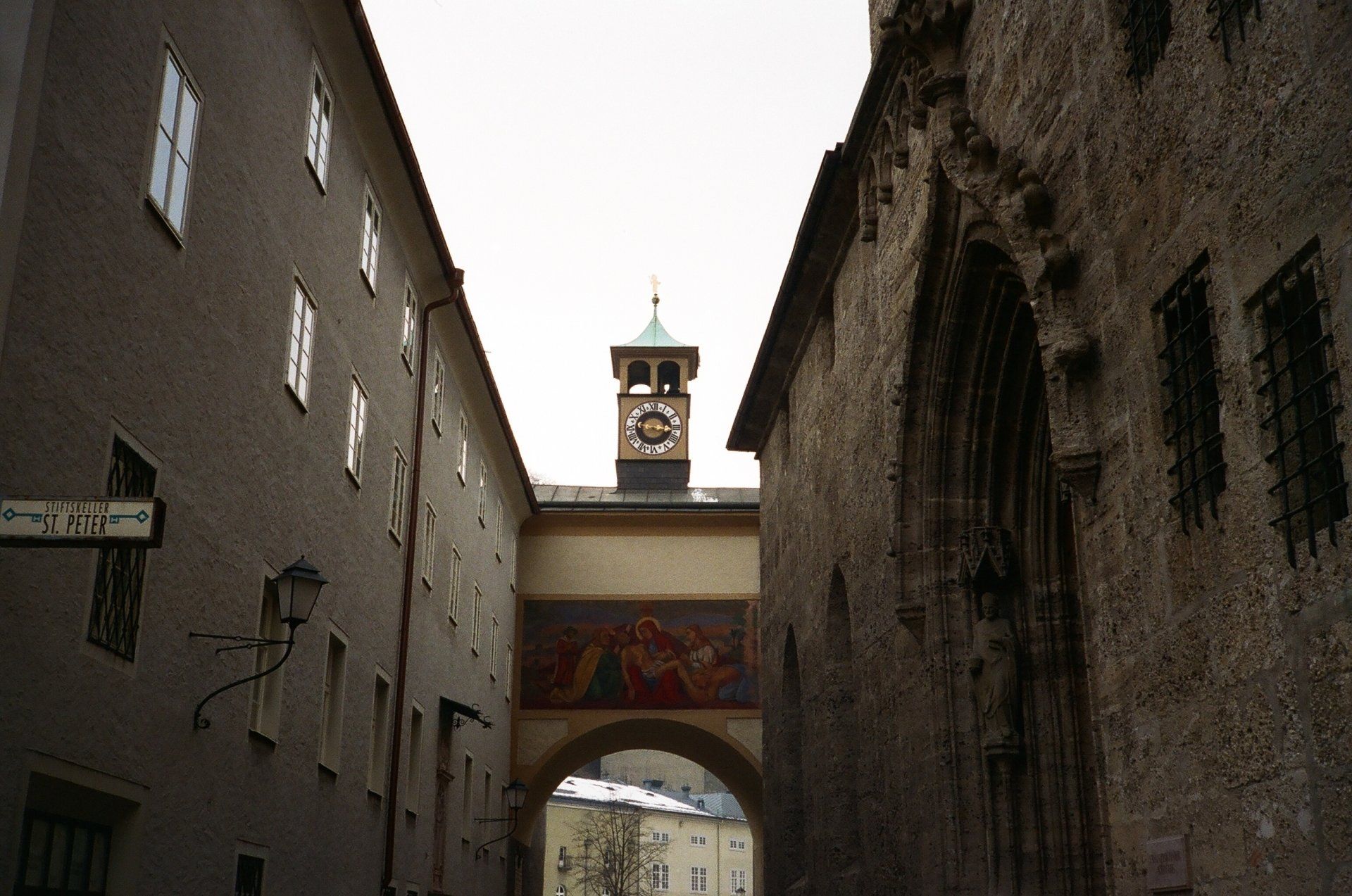 A clock tower in the middle of a narrow alleyway