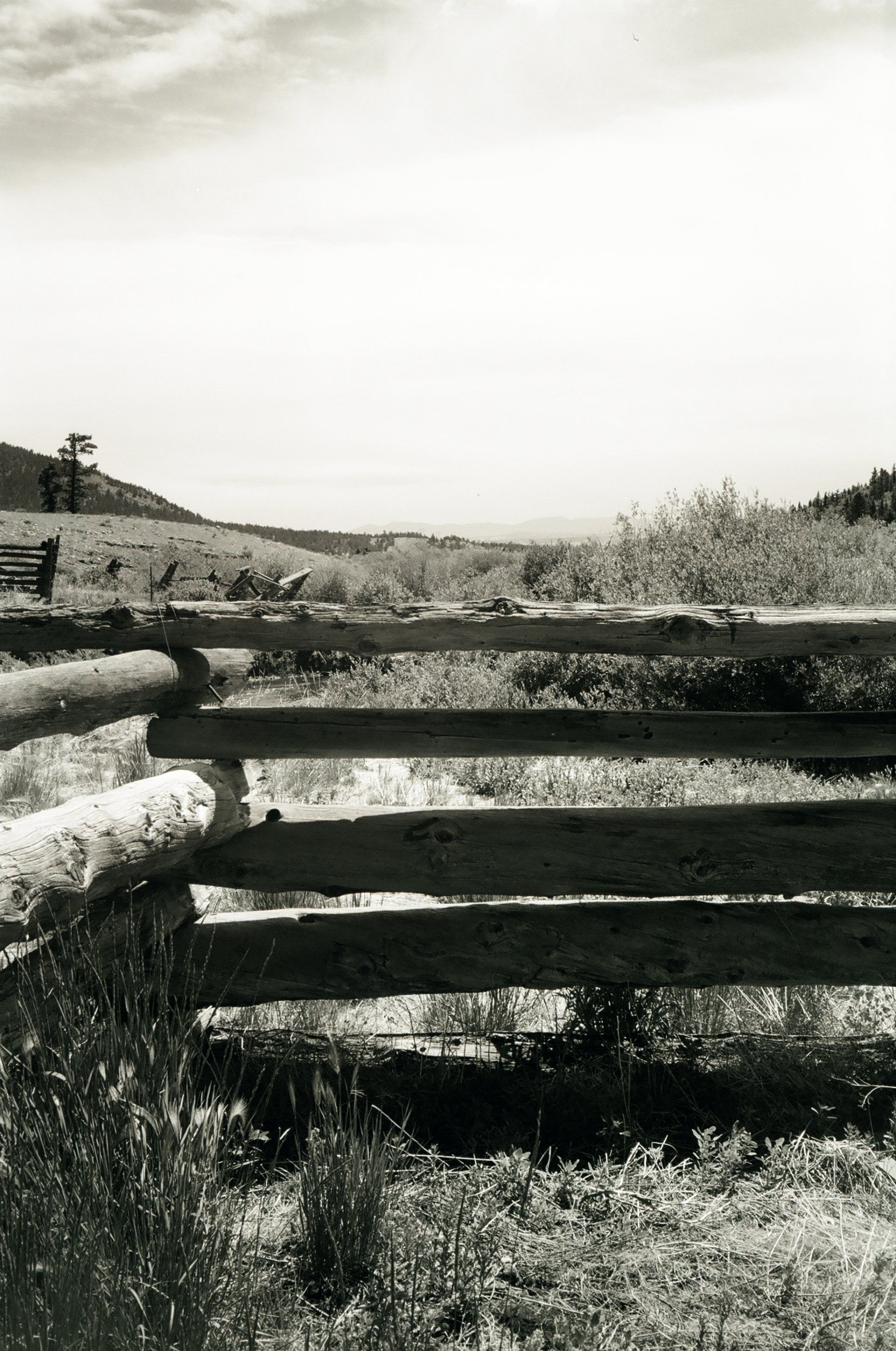 A black and white photo of a wooden fence in a field
