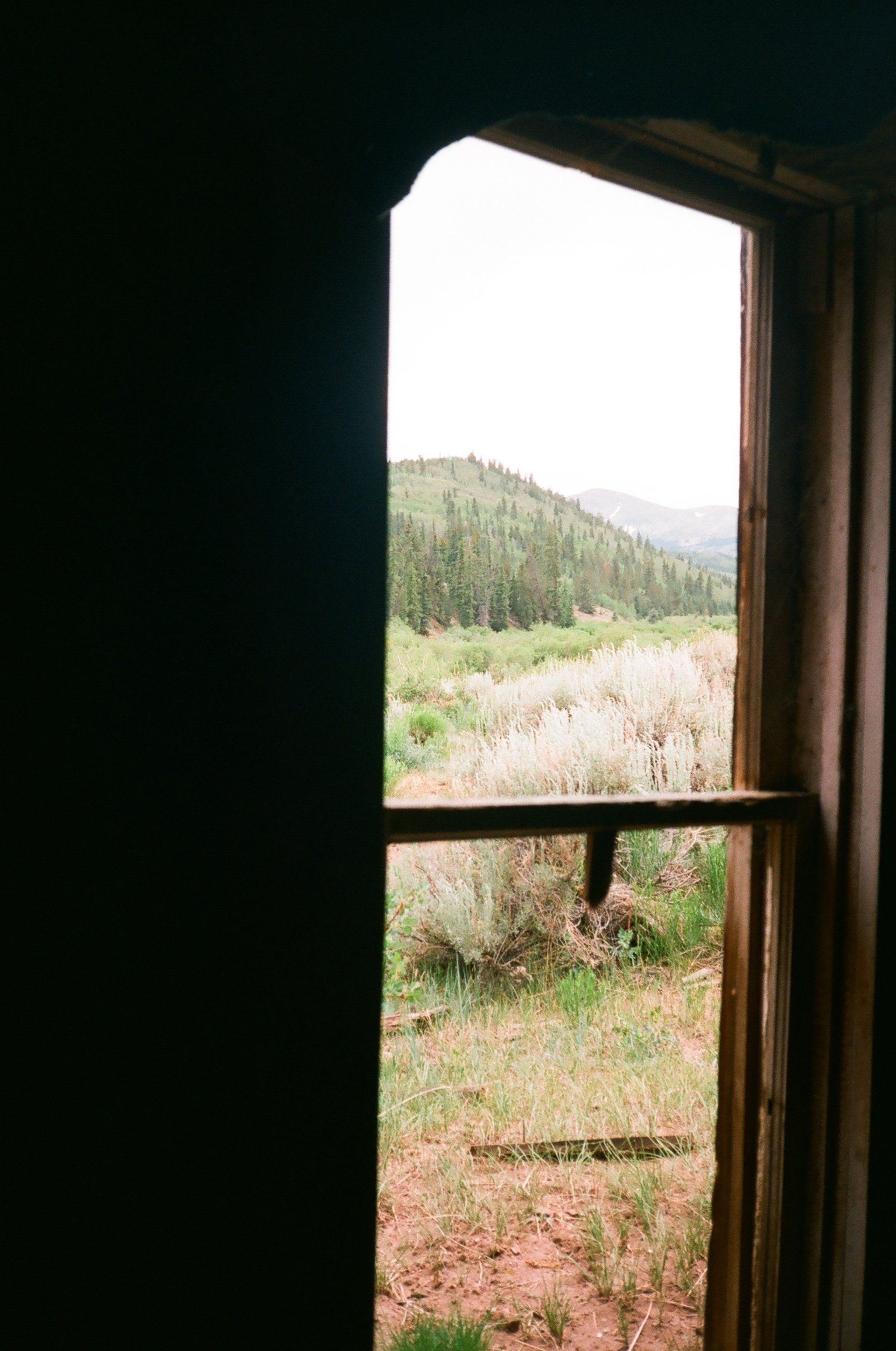 A window with a view of a field and mountains.