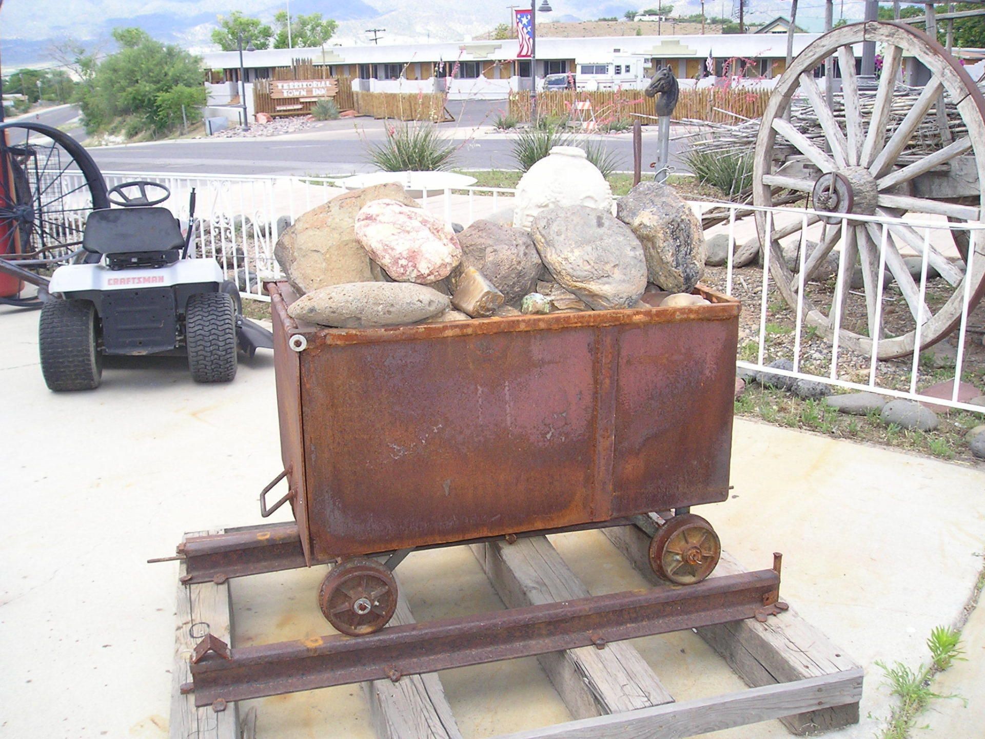 A rusty cart filled with rocks sits on a wooden pallet