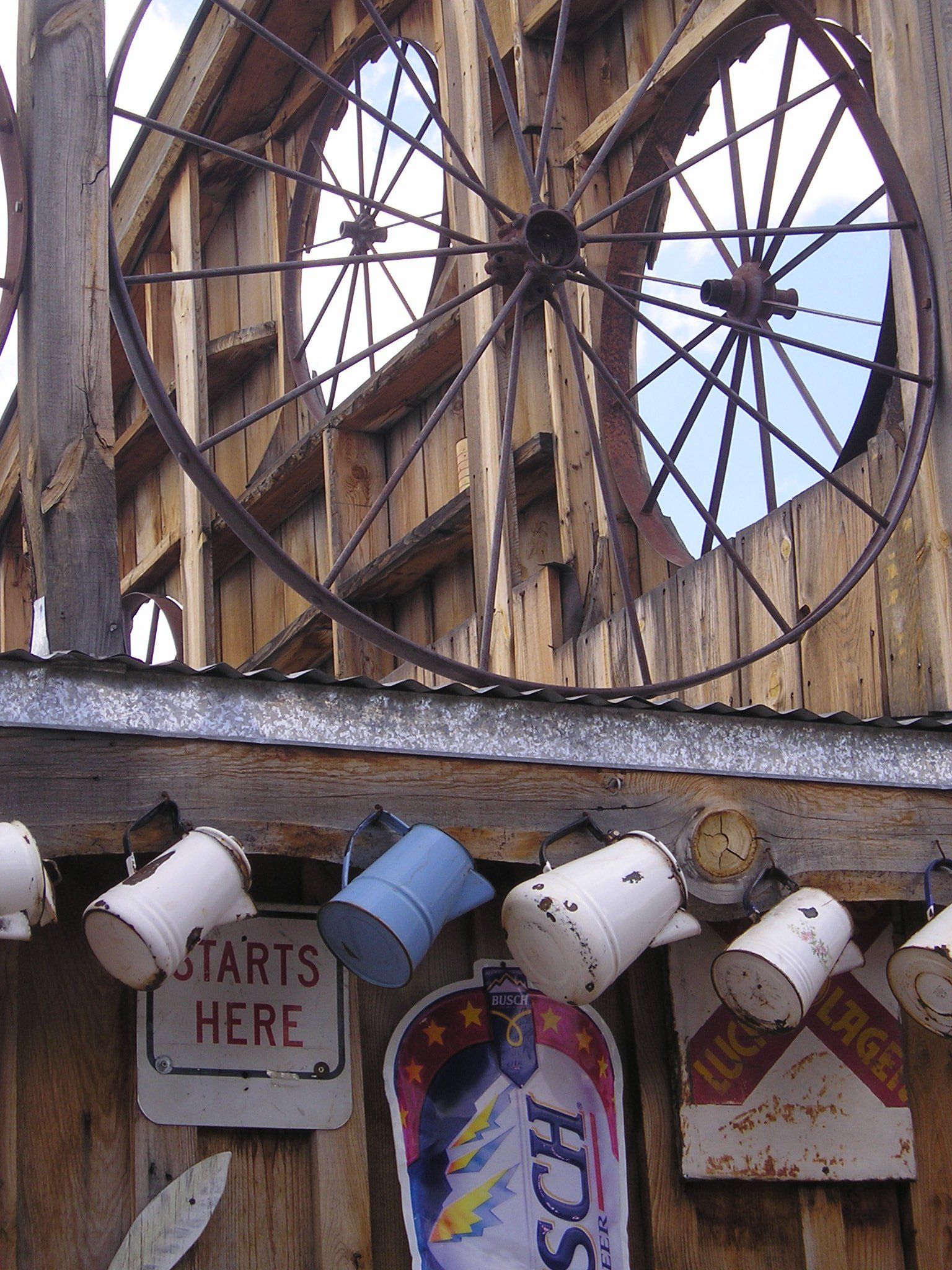 A sign that says starts here hangs on a wooden building