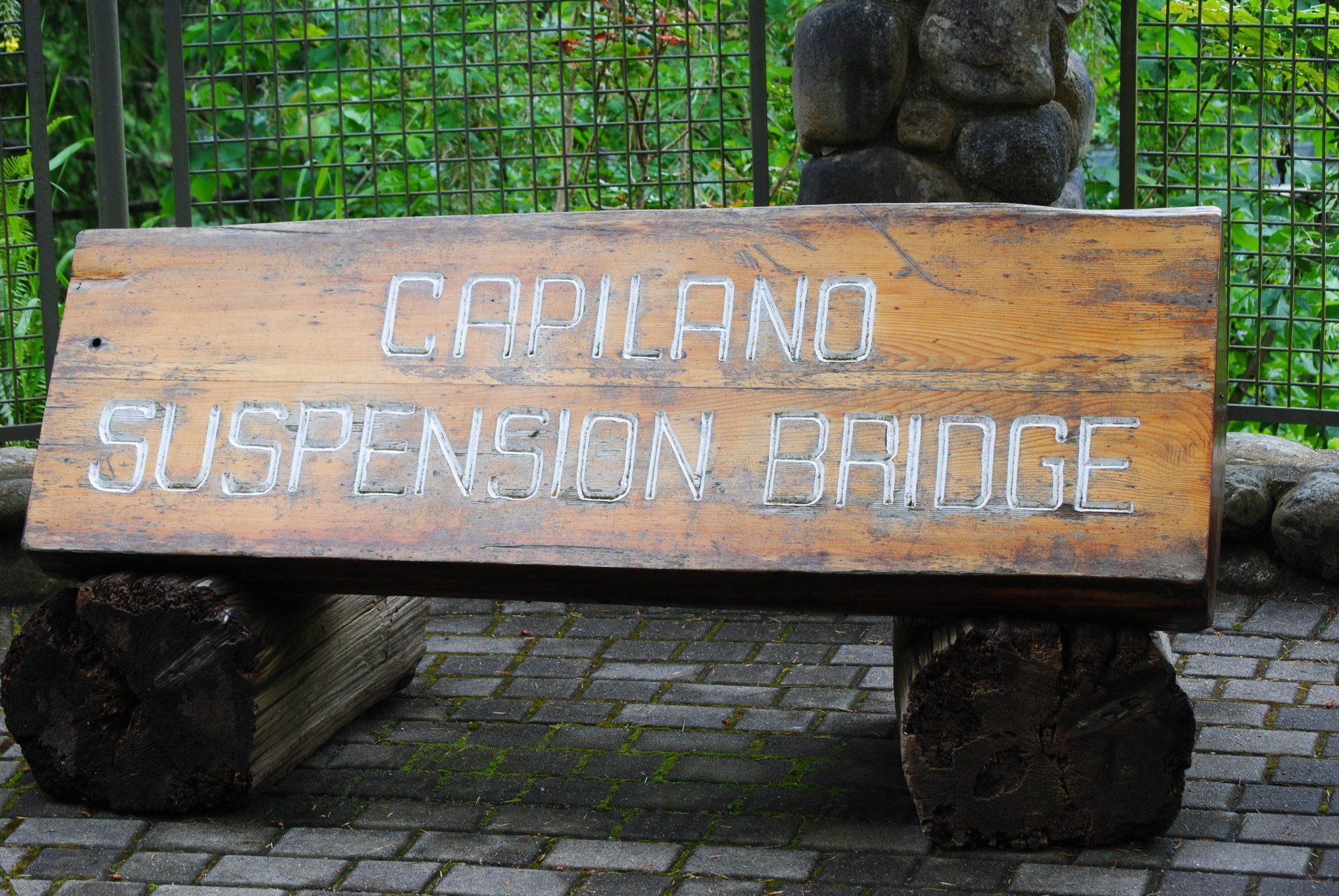 A wooden bench with the words capiland suspension bridge written on it