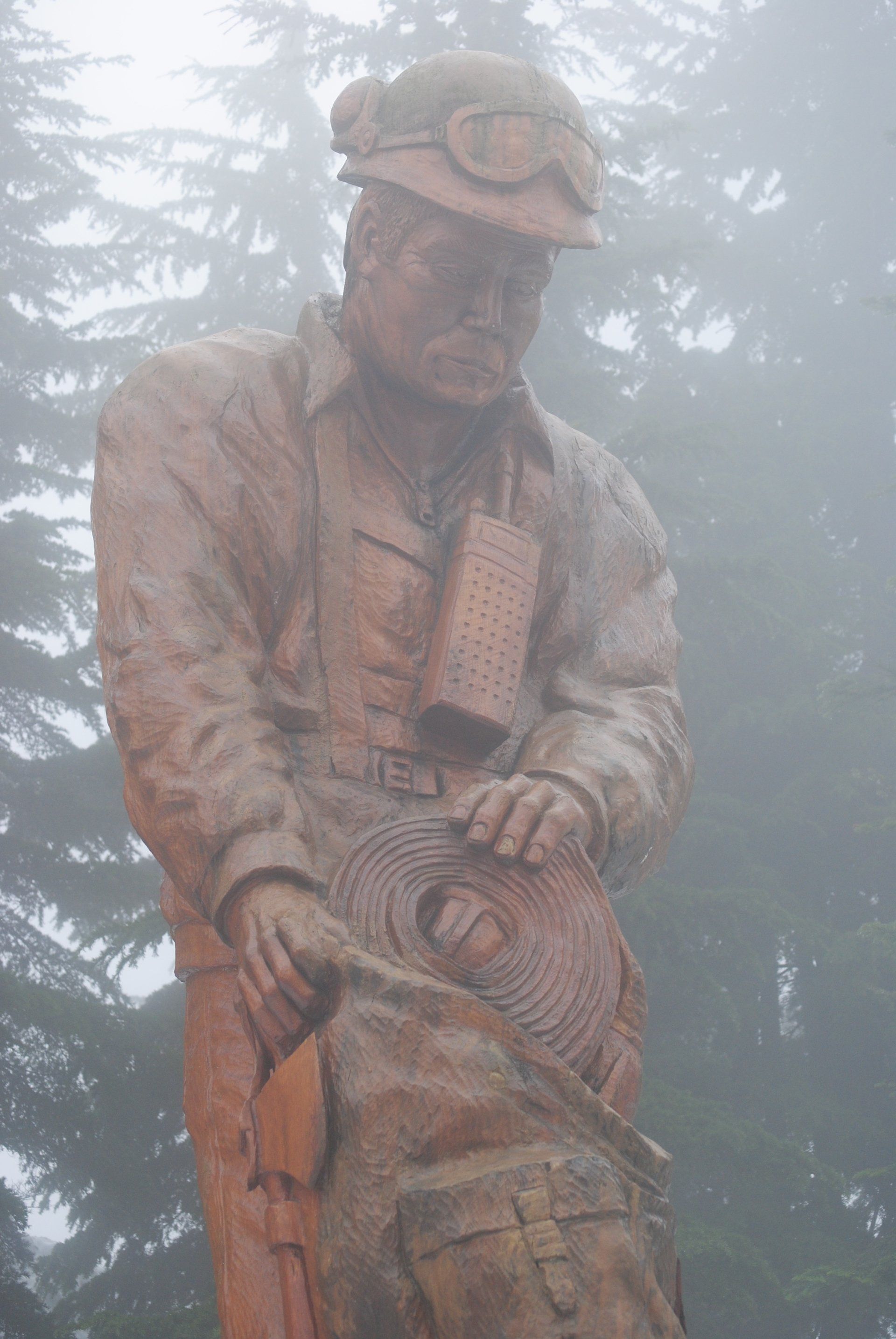 A statue of a man wearing a helmet and goggles is standing in the fog.