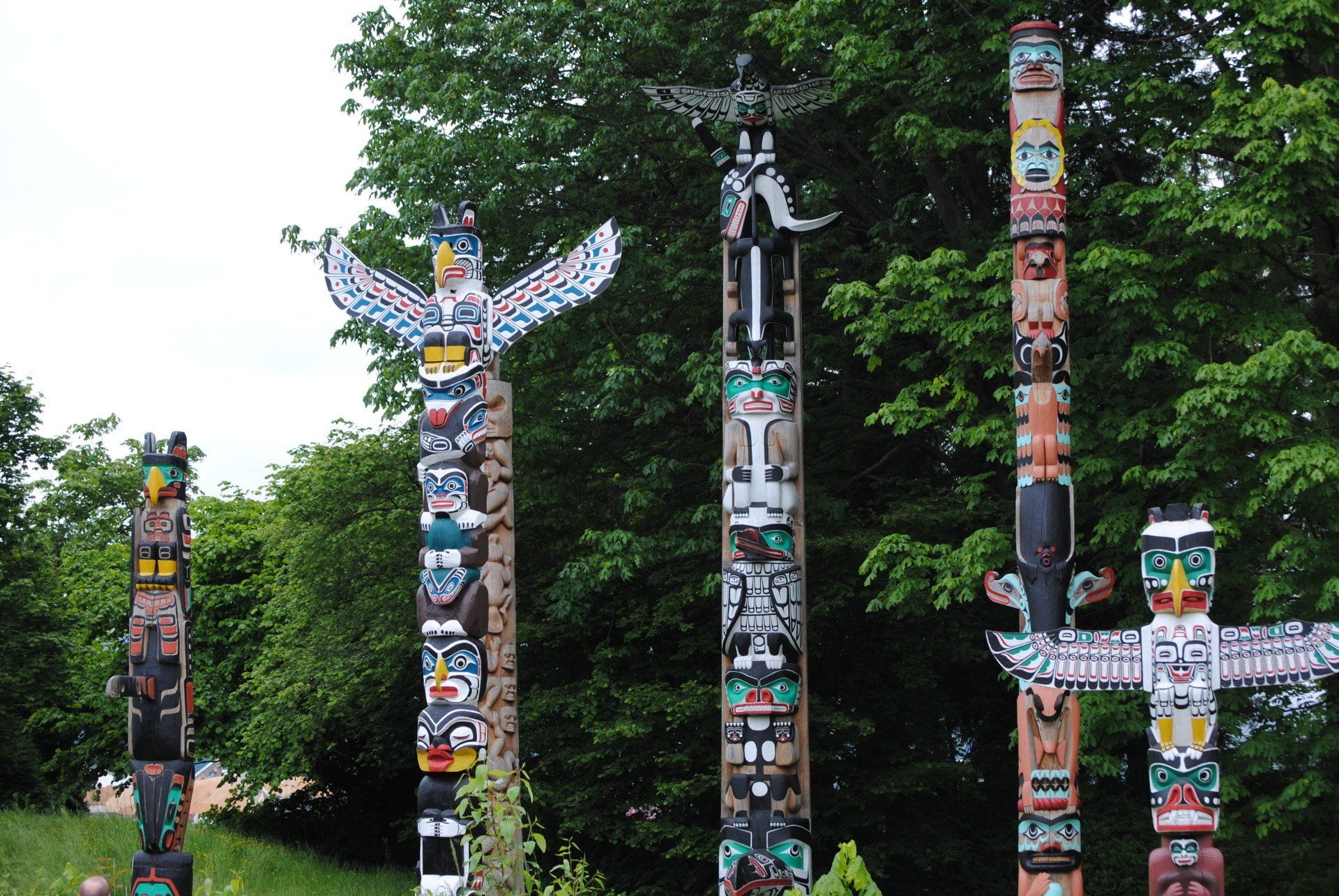 A row of totem poles in a park with trees in the background