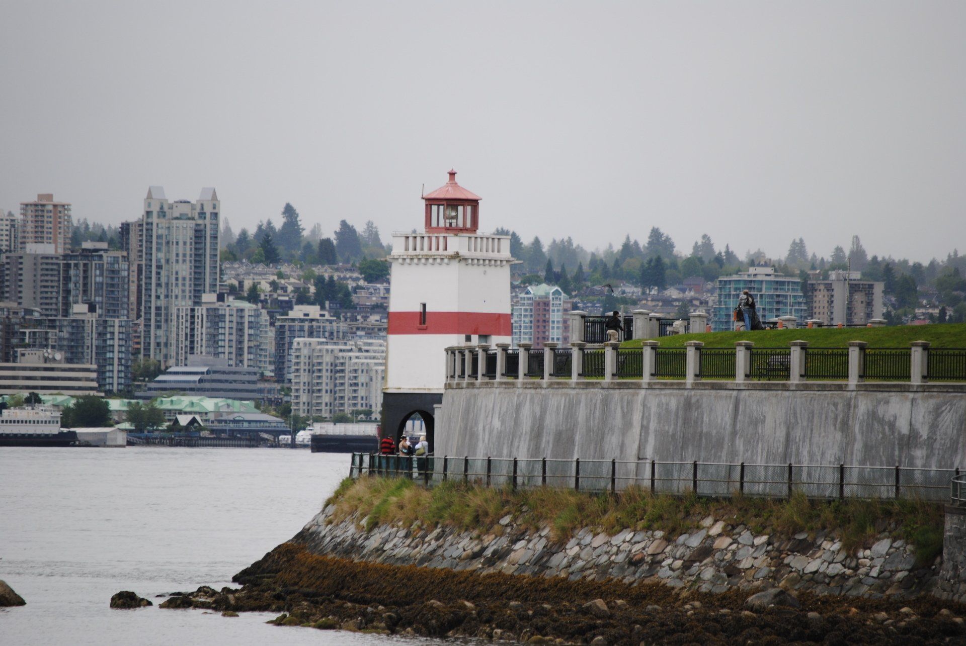 A red and white lighthouse on a cliff overlooking a body of water