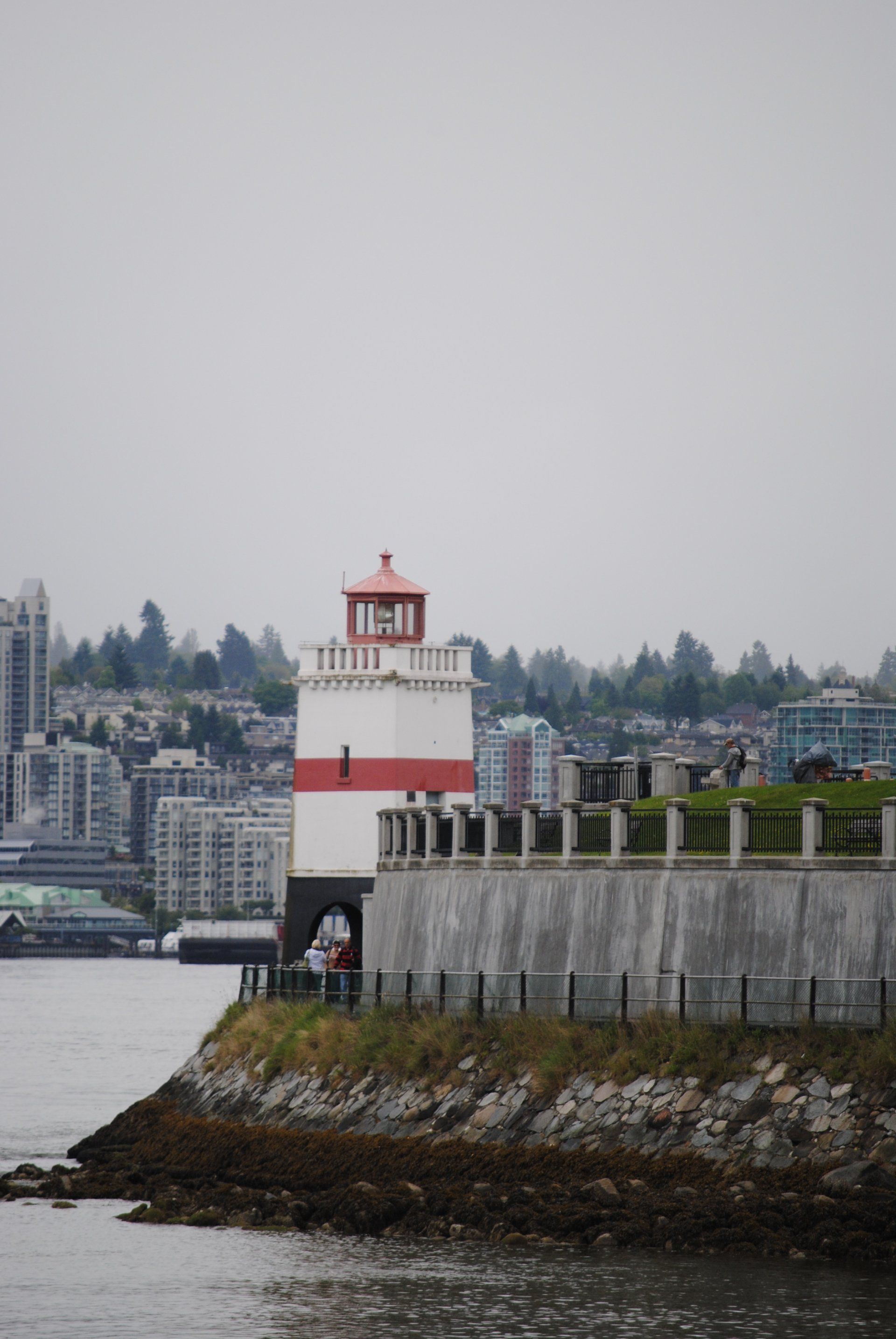 A lighthouse sits on the shore of a body of water