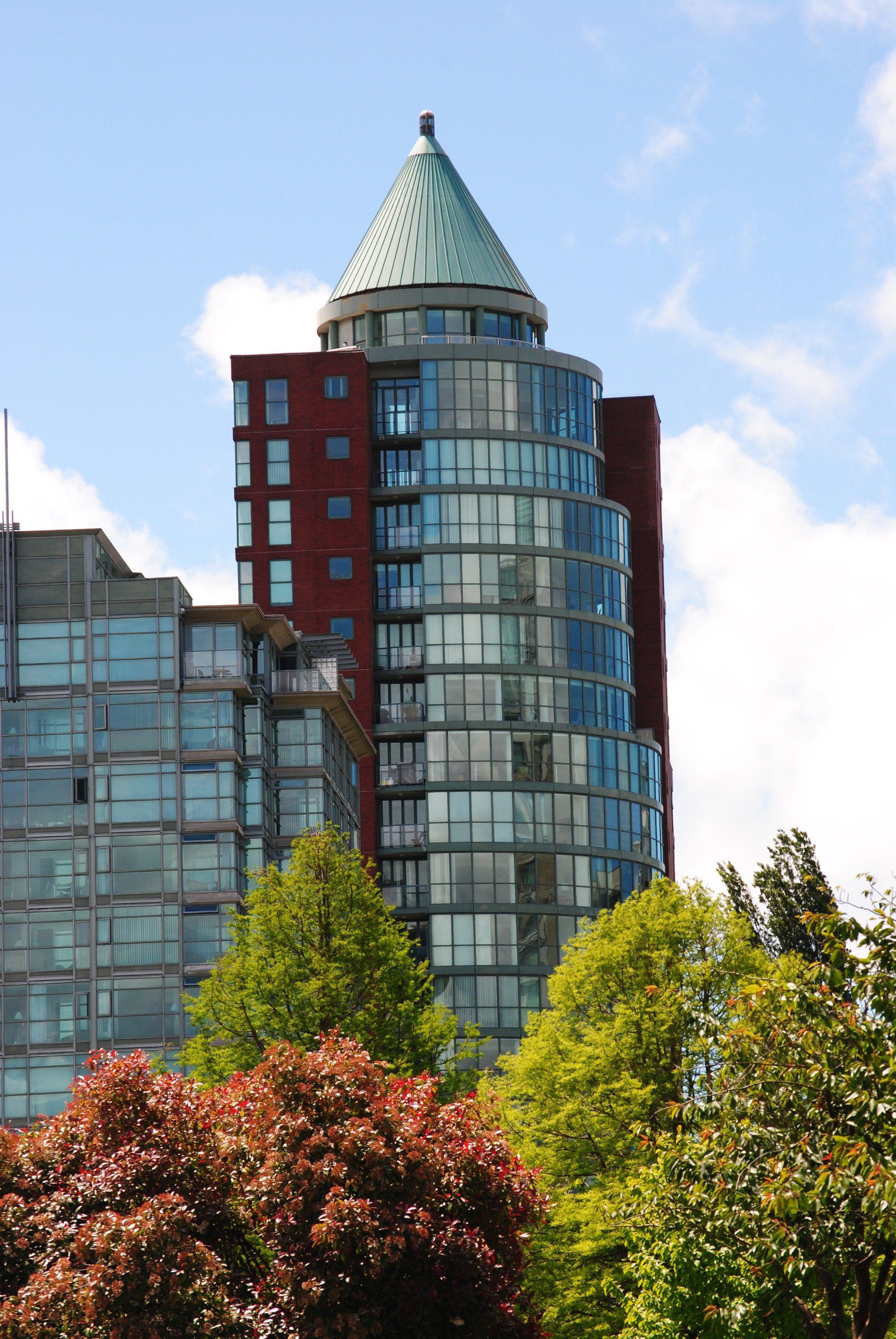 A tall building with a green roof is surrounded by trees