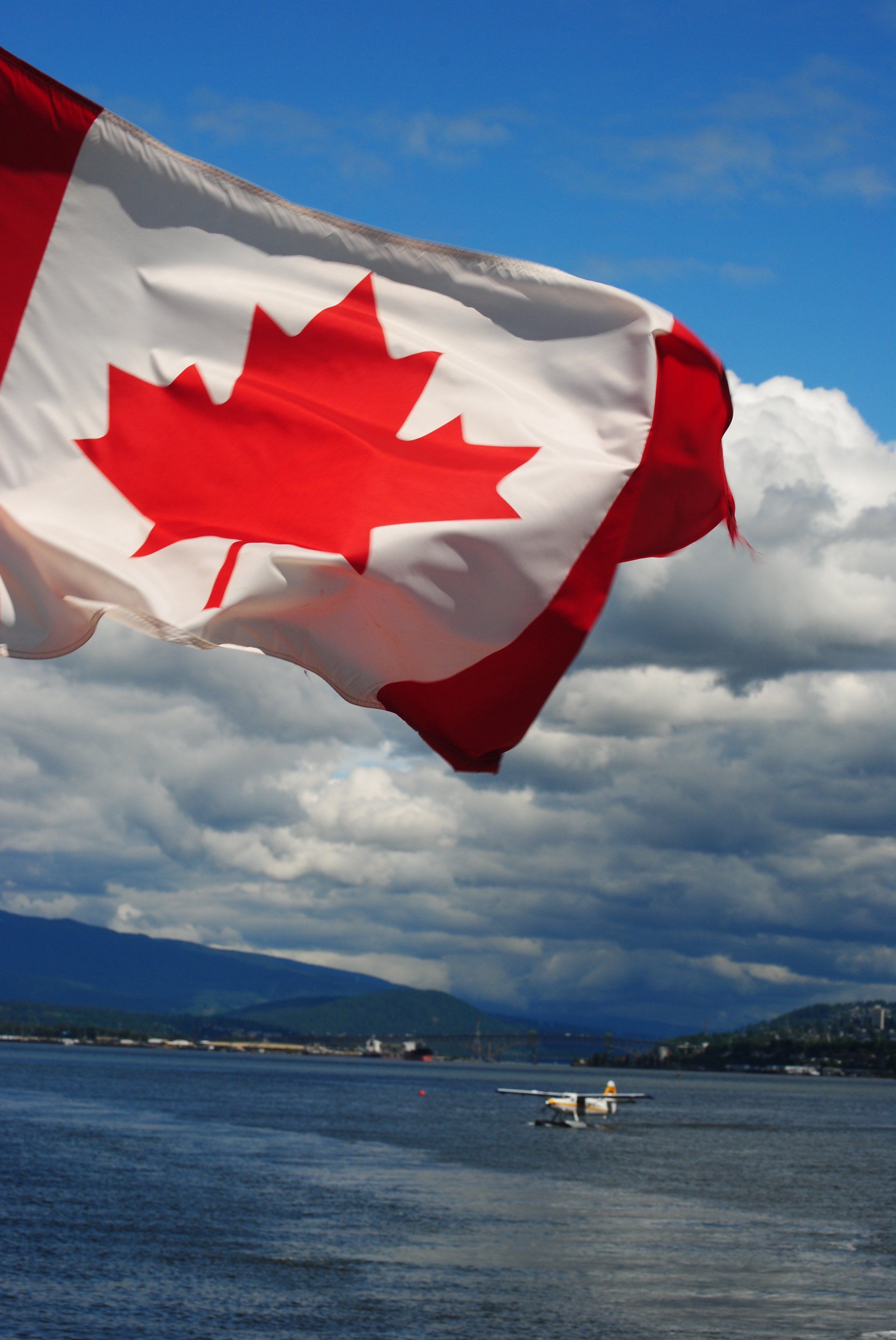 A canadian flag is flying over a body of water
