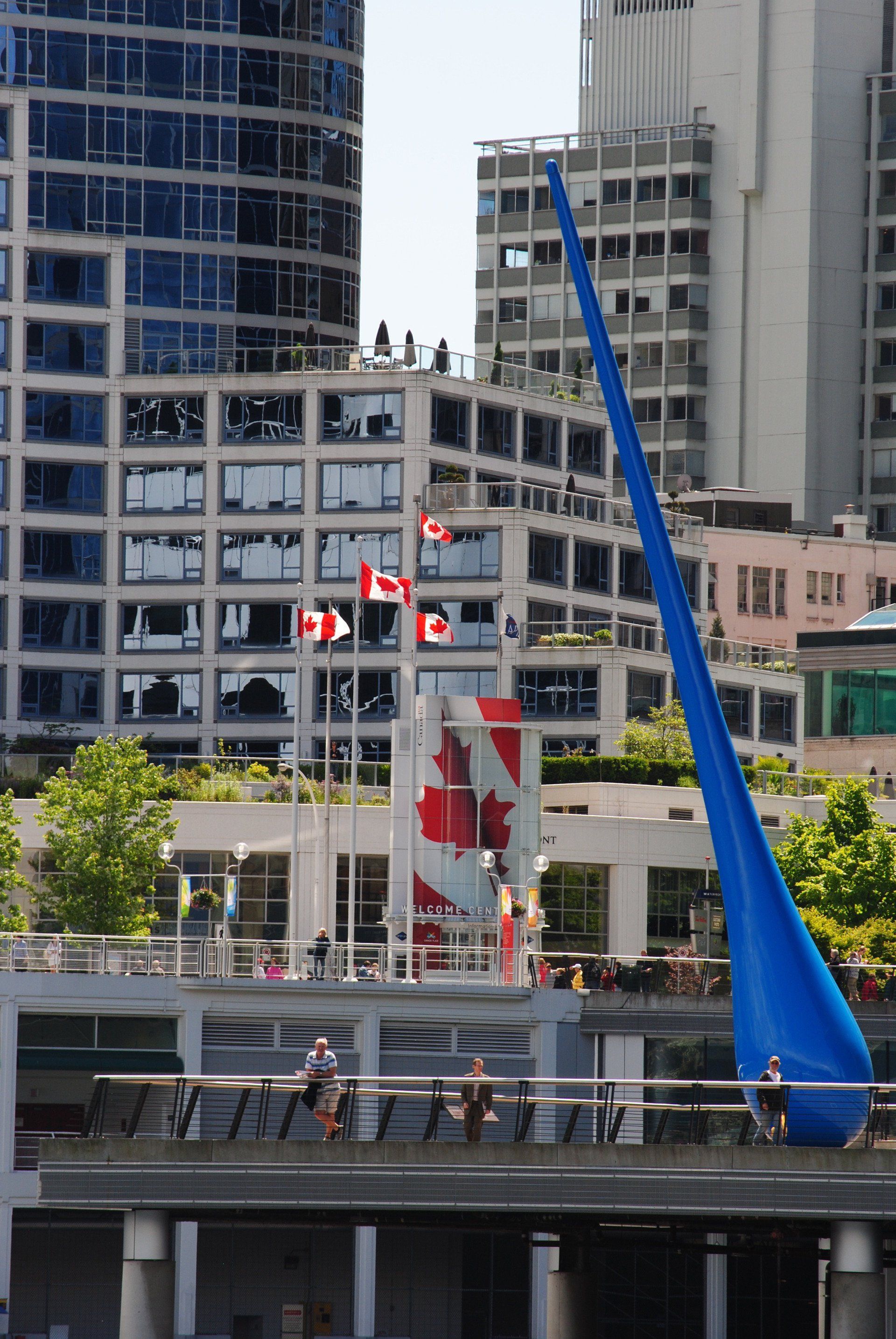 A canadian flag is flying in front of a tall building