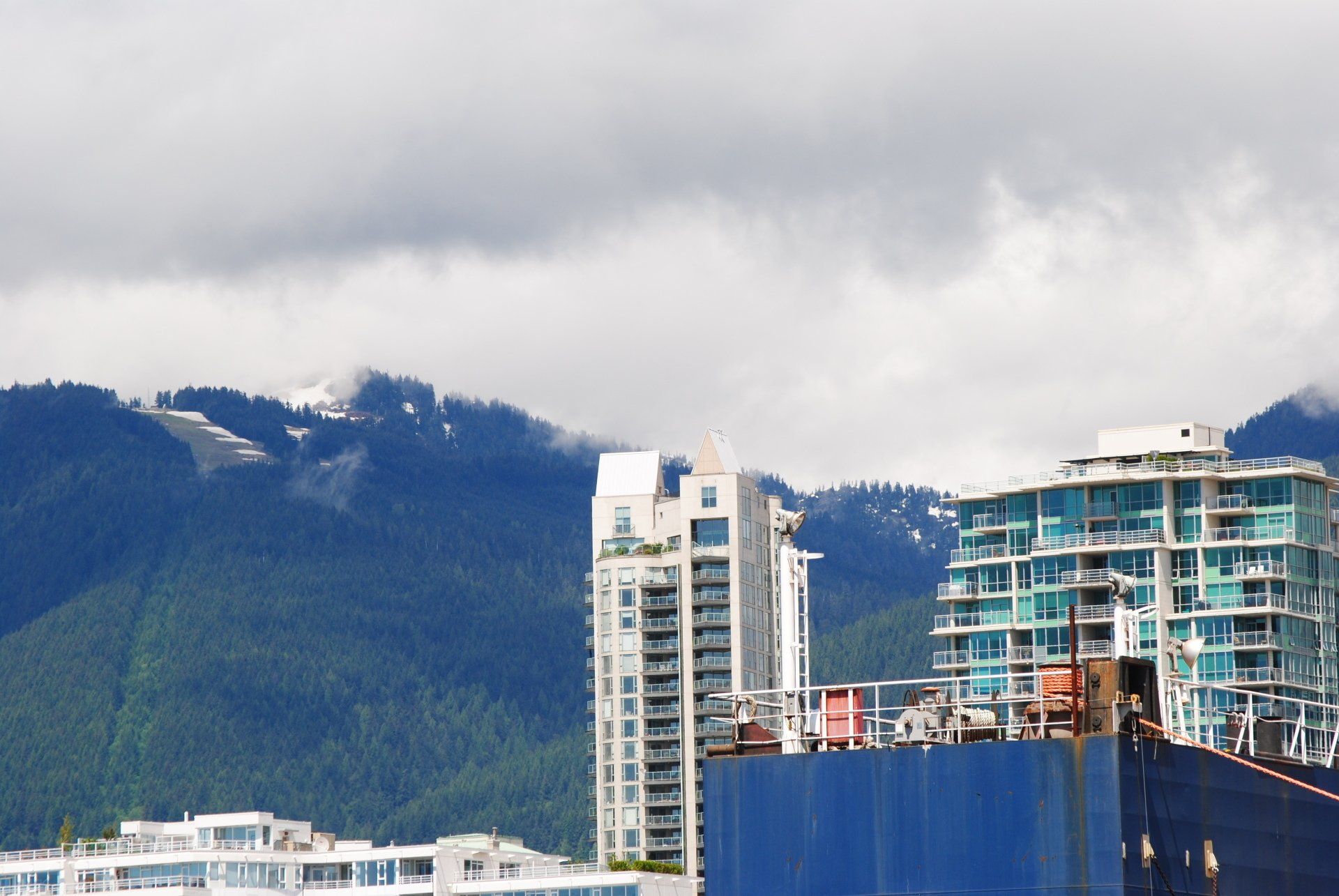A large ship is docked in a harbor with mountains in the background